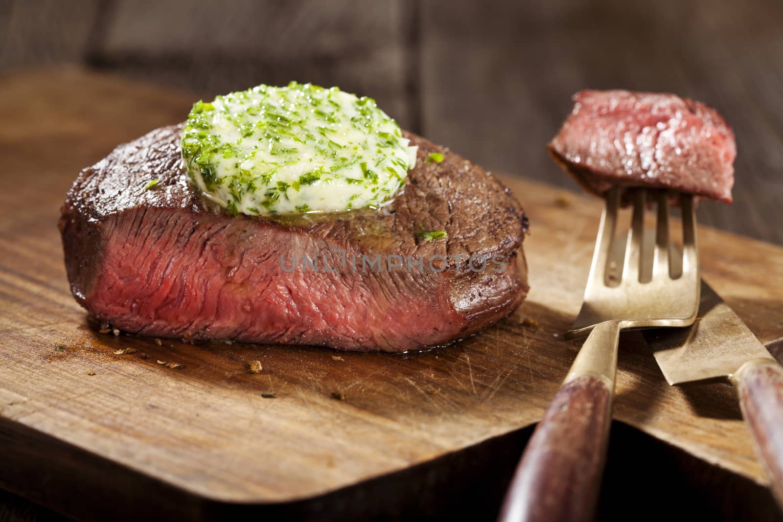 Steak with green butter on wooden board