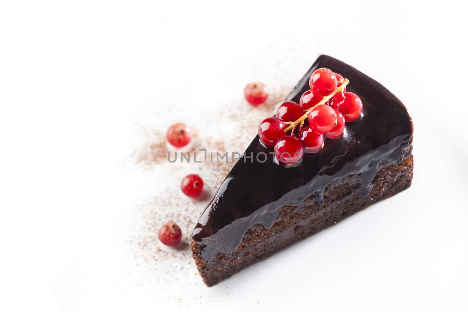 Piece of chocolate cake with red berries on white background