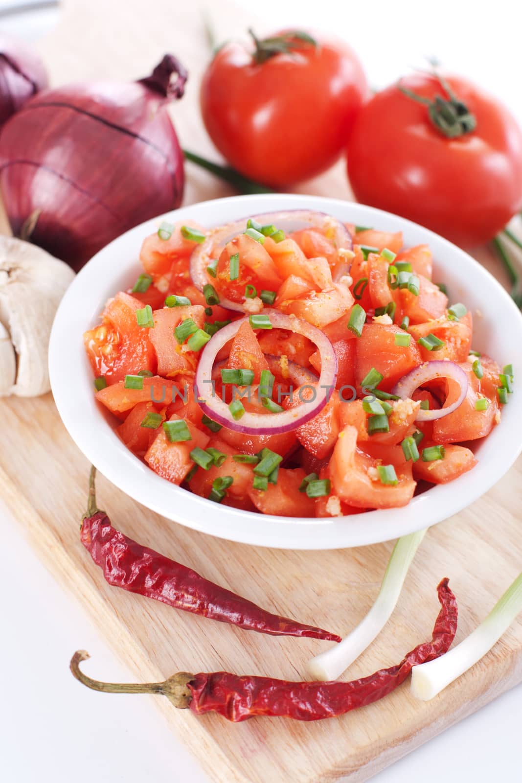 Salsa in a bowl on a wooden board and the ingredients: tomatoes, onions, garlic, chili pepper