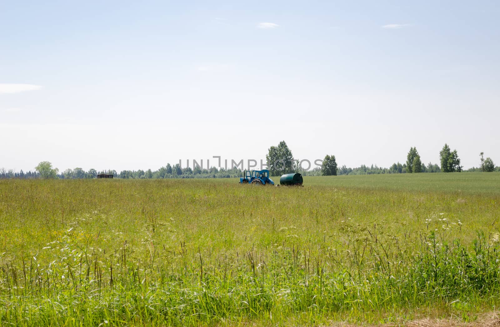 working tractor with water tank in pasture meadow by sauletas