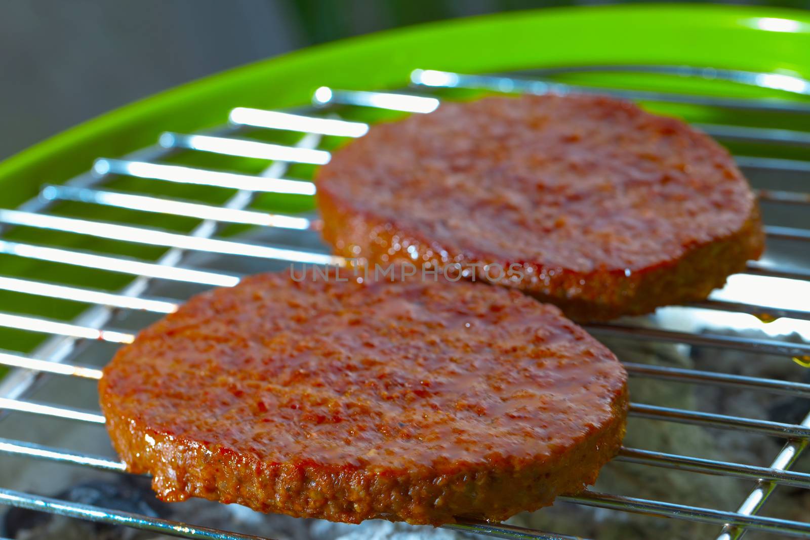 Hamburgers over a bbq, focus over low part of first hamburger