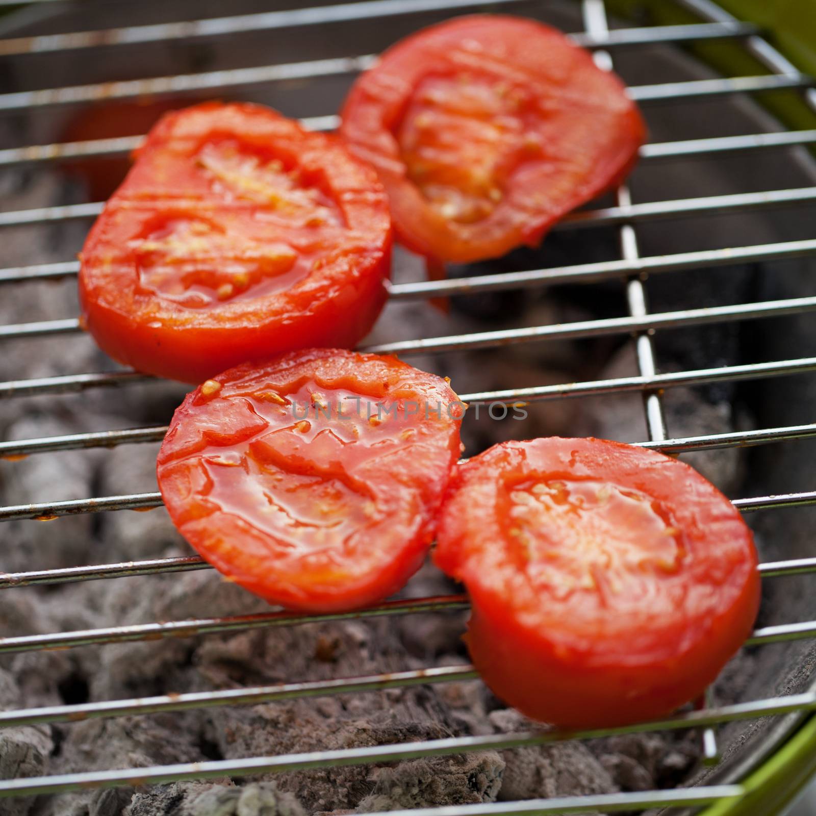 Tomatoes over metallic barbeque grill, close up