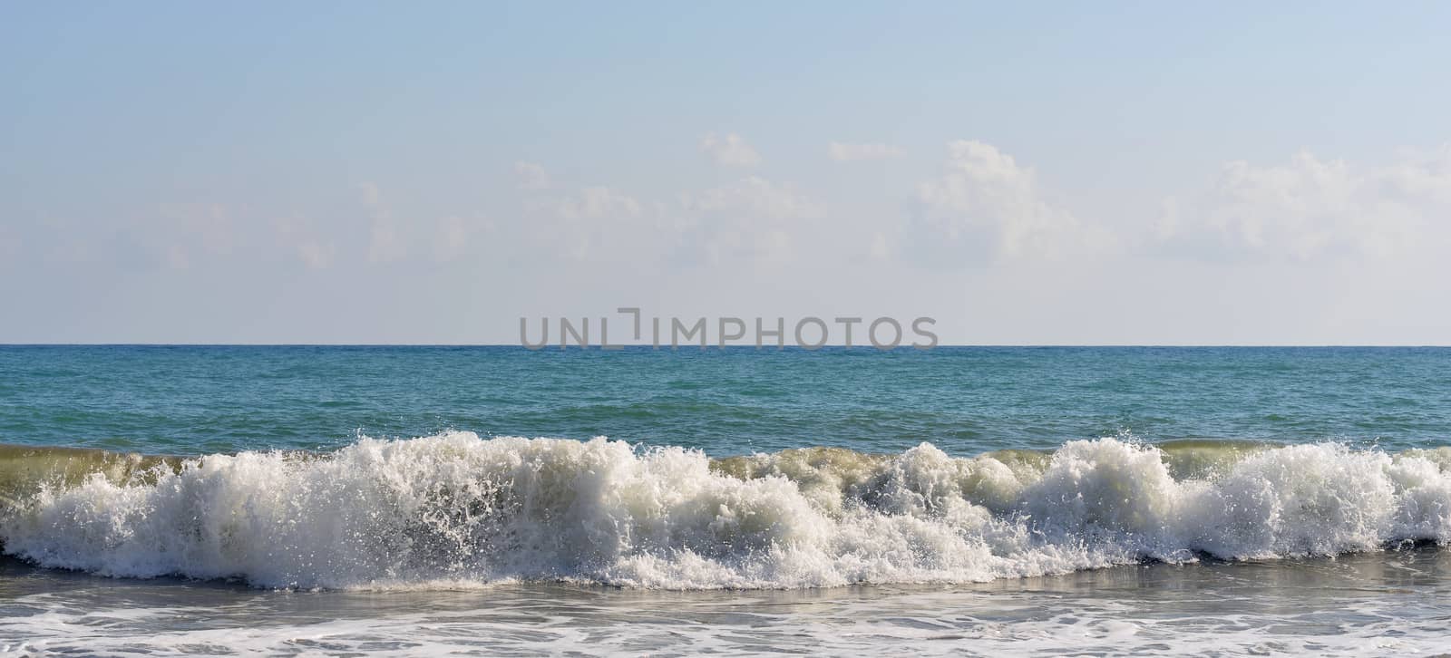 Sea wave rolled ashore. Blue sky in the background