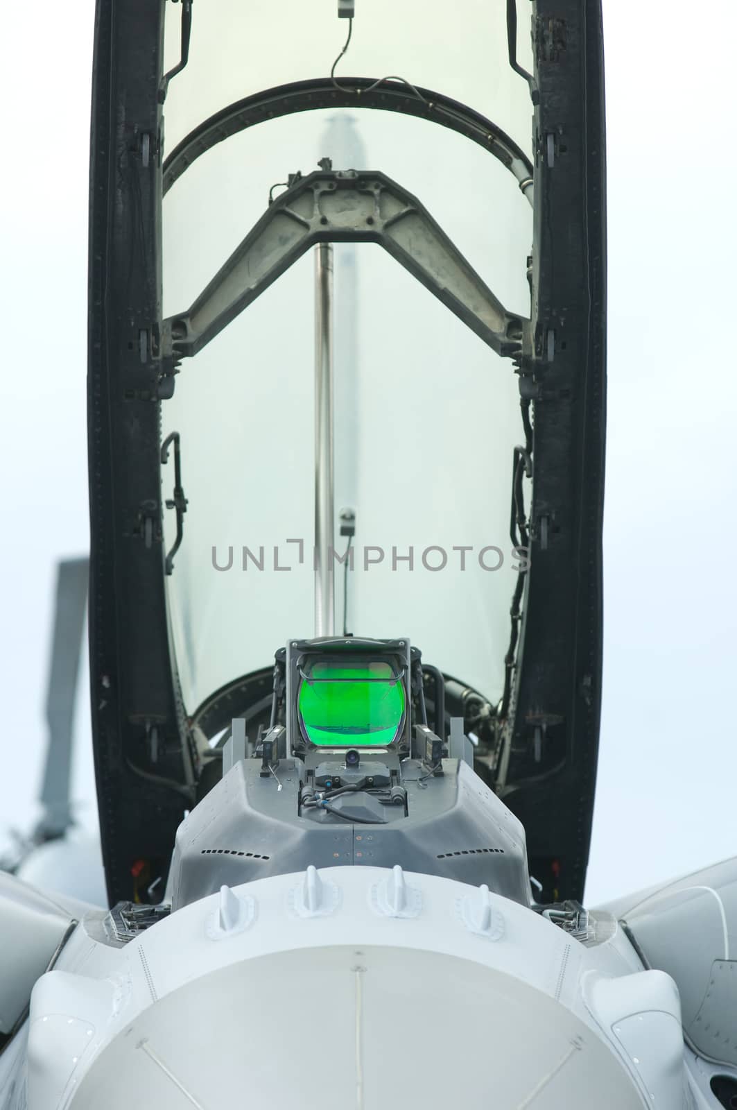 Front view of the open cockpit of a fighter jet with green head-up display.