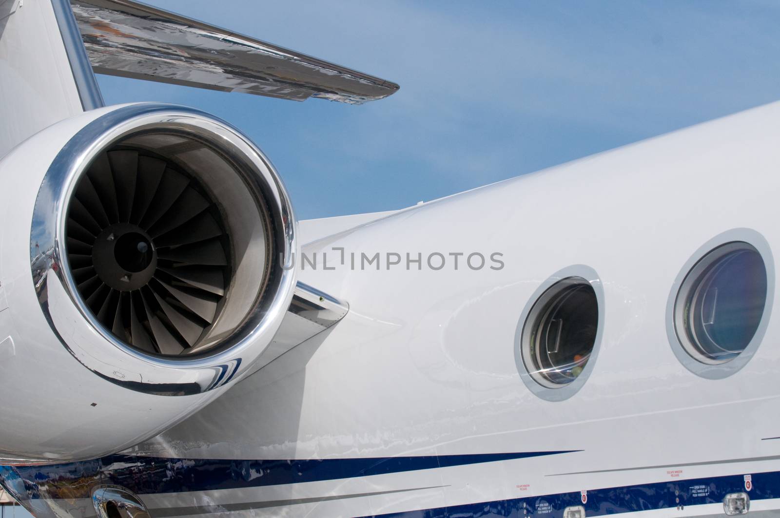 Engine, windows and tail fin of white, luxury corporate jet