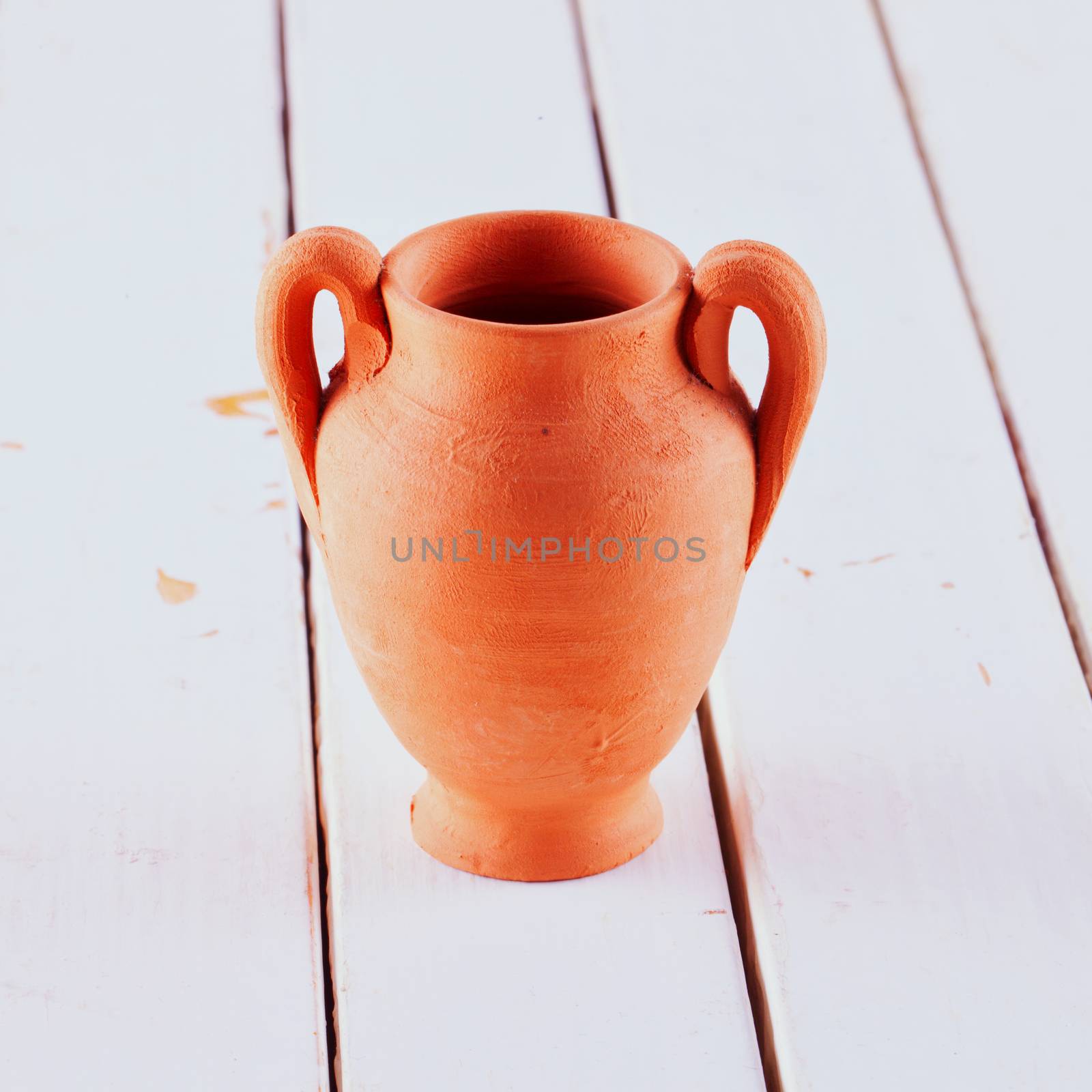 Amphora in terracotta over white wooden table