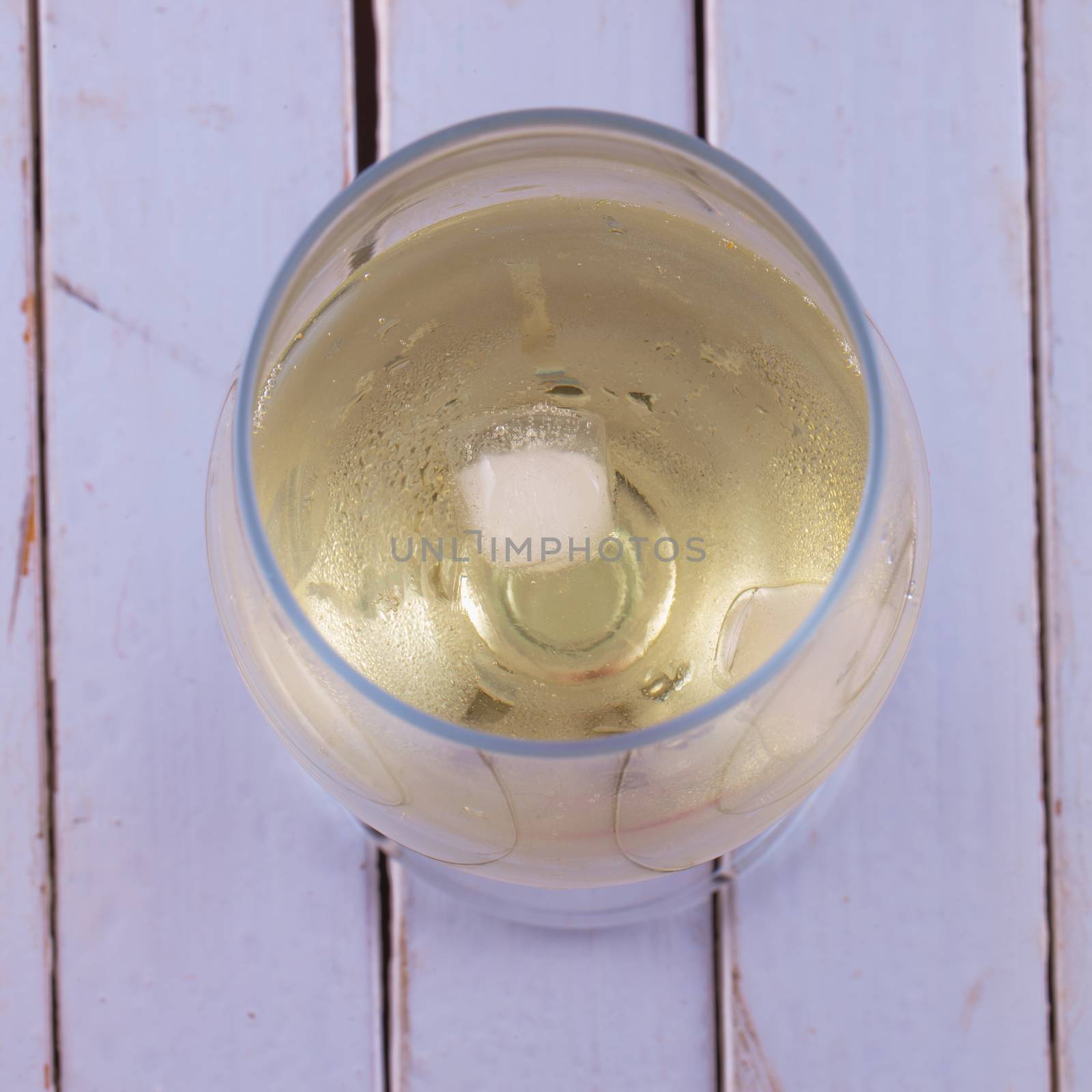 White wine with ice, over wooden white table