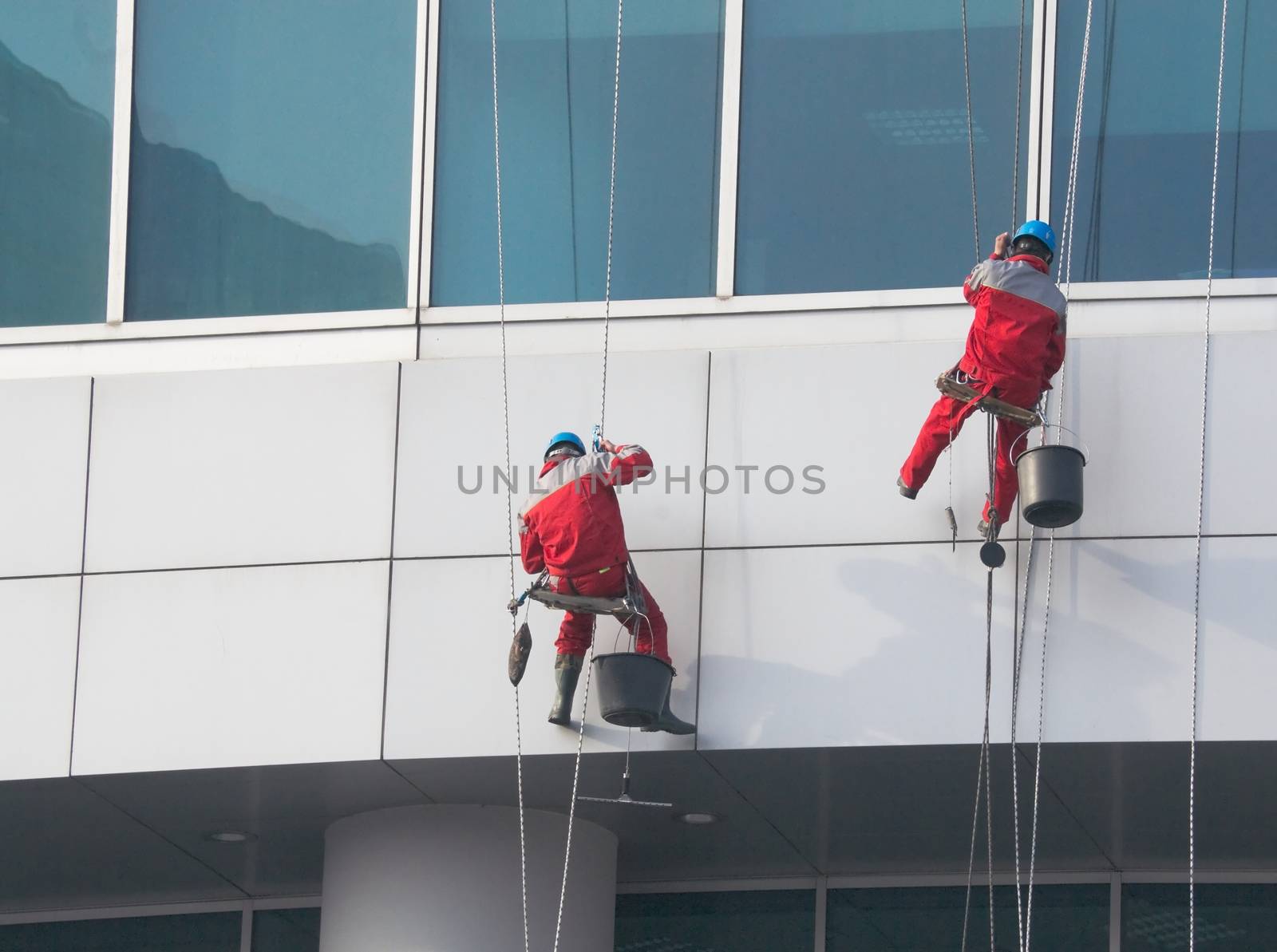 Climbers - window cleaners perform the work at wall of an office building