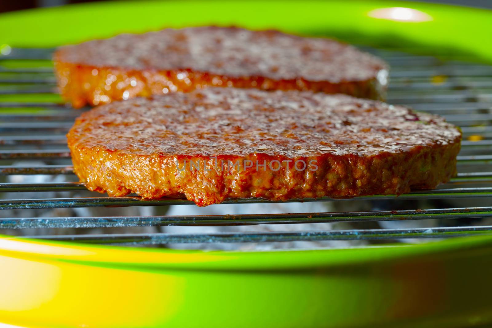 Hamburgers over the grill of a green bbq