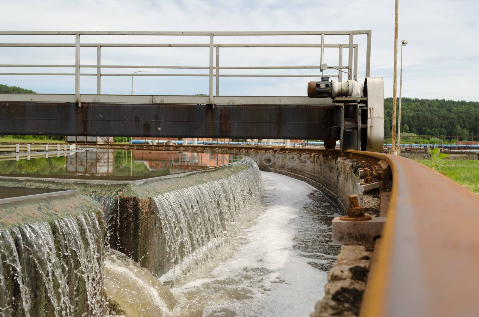 Sewage treatment mechanism spinning and filtering water flow in basin.