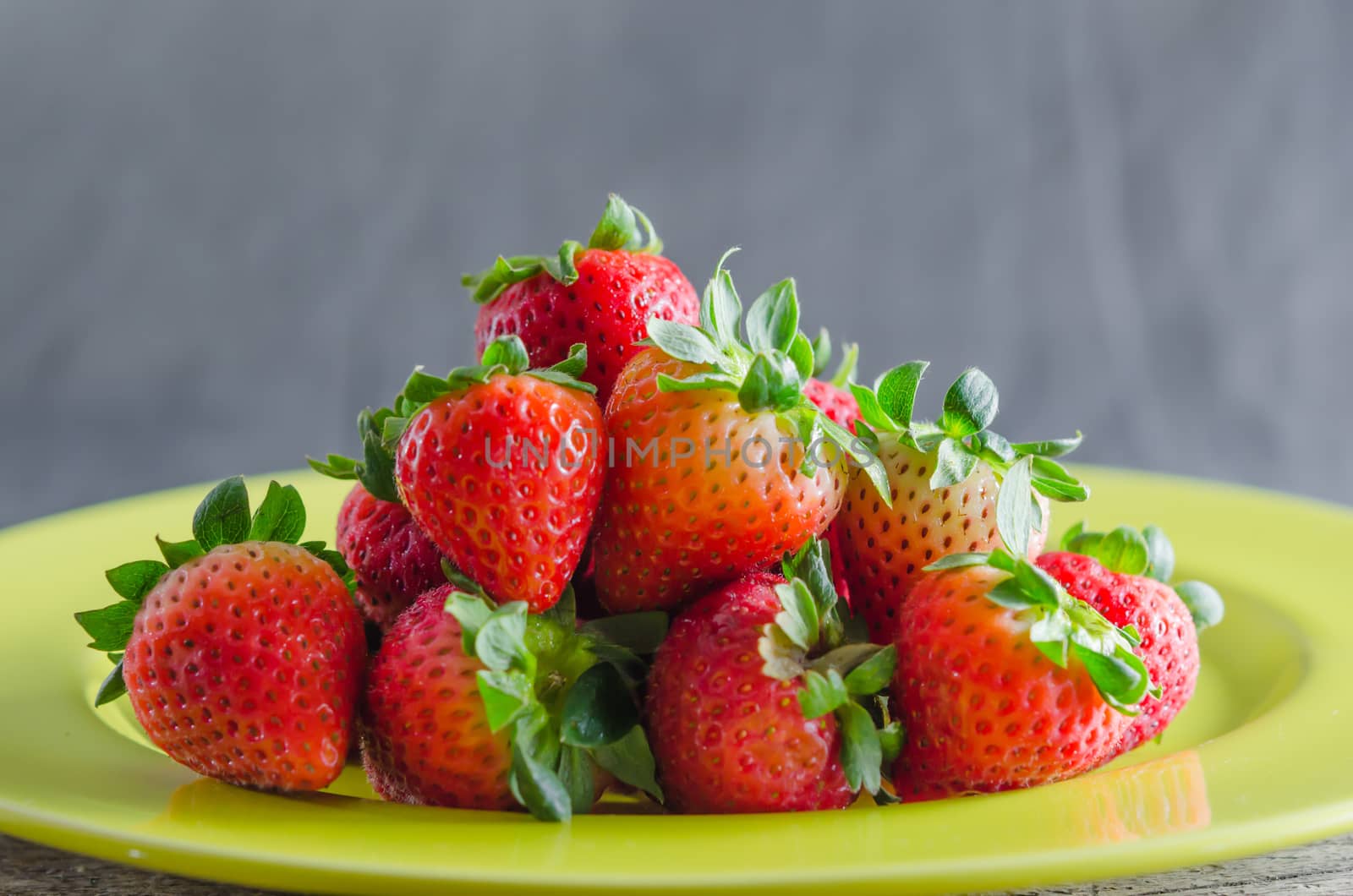 still life of fresh red strawberries on dish over wooden background