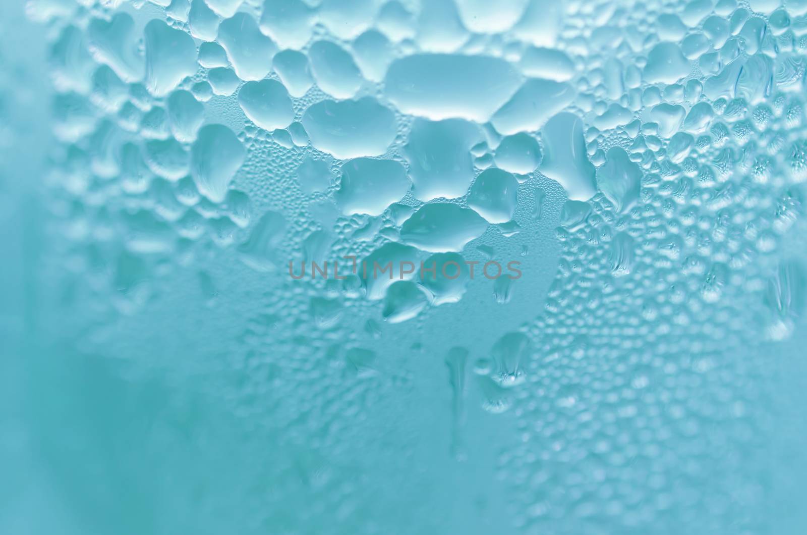 Water droplets on the glass with a colored background. Drops of water.