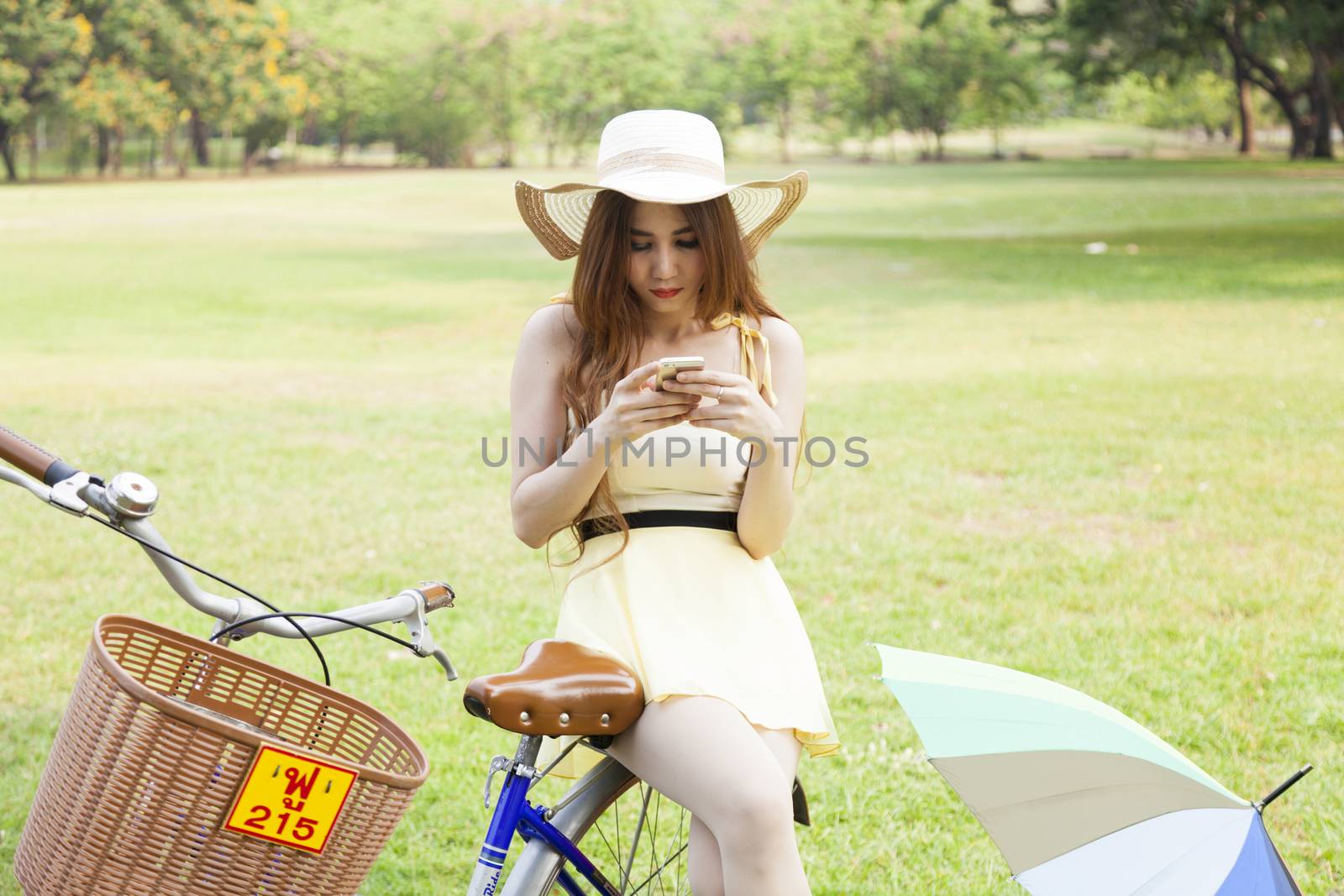 Woman play smart phone.on bike in lawn.in park.