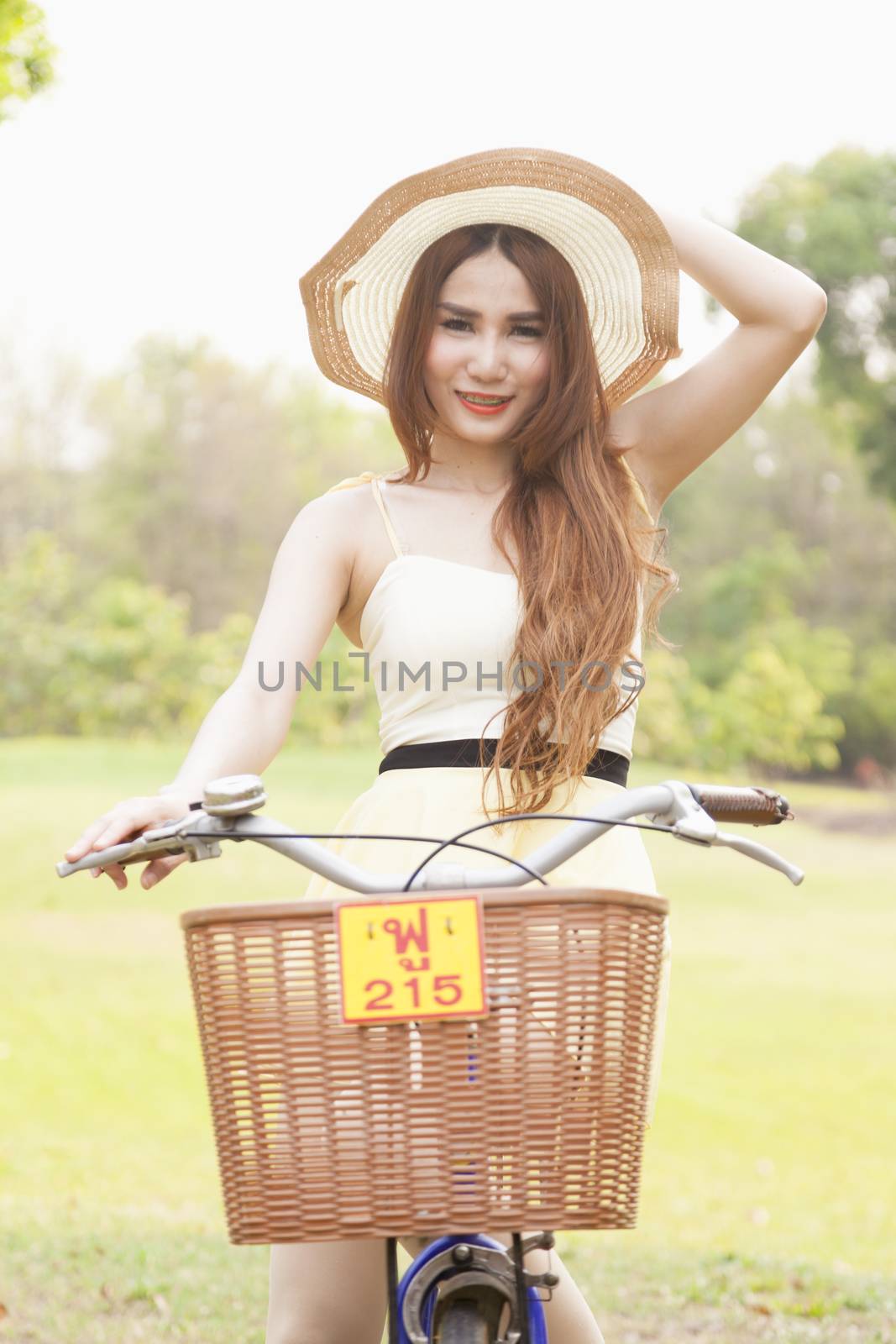 Woman riding a bicycle. Woman with hat riding a bicycle in the park.