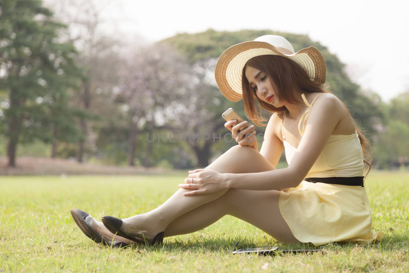 Woman using a phone Sitting on the grass in the park.
