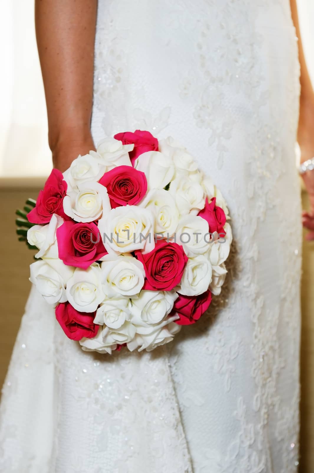 Closeup of brides bouquet of red and white flowers and dress detail