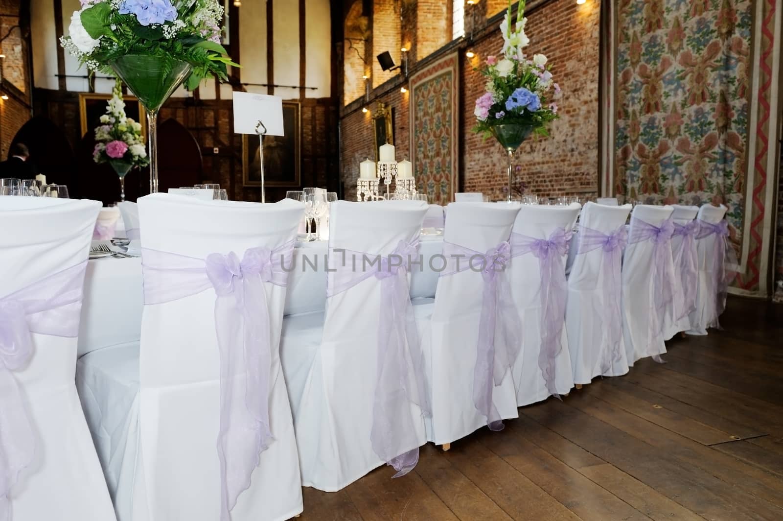 Back of chairs showing white and lilac covers at wedding reception
