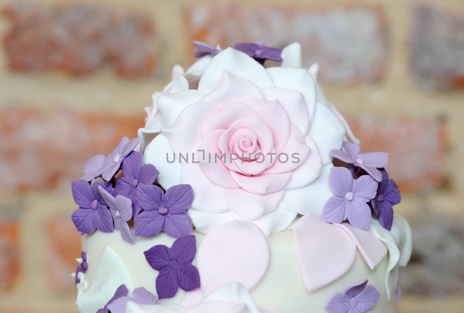 Pink and purple floral detail on top of wedding cake