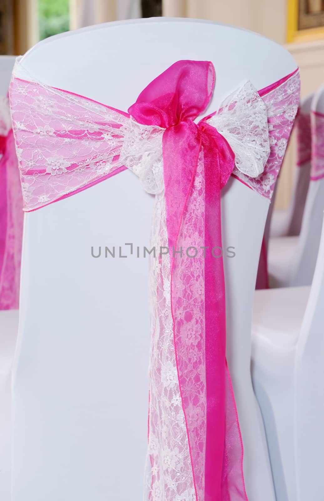 Pink and white chair cover at wedding ceremony showing closeup bow detail