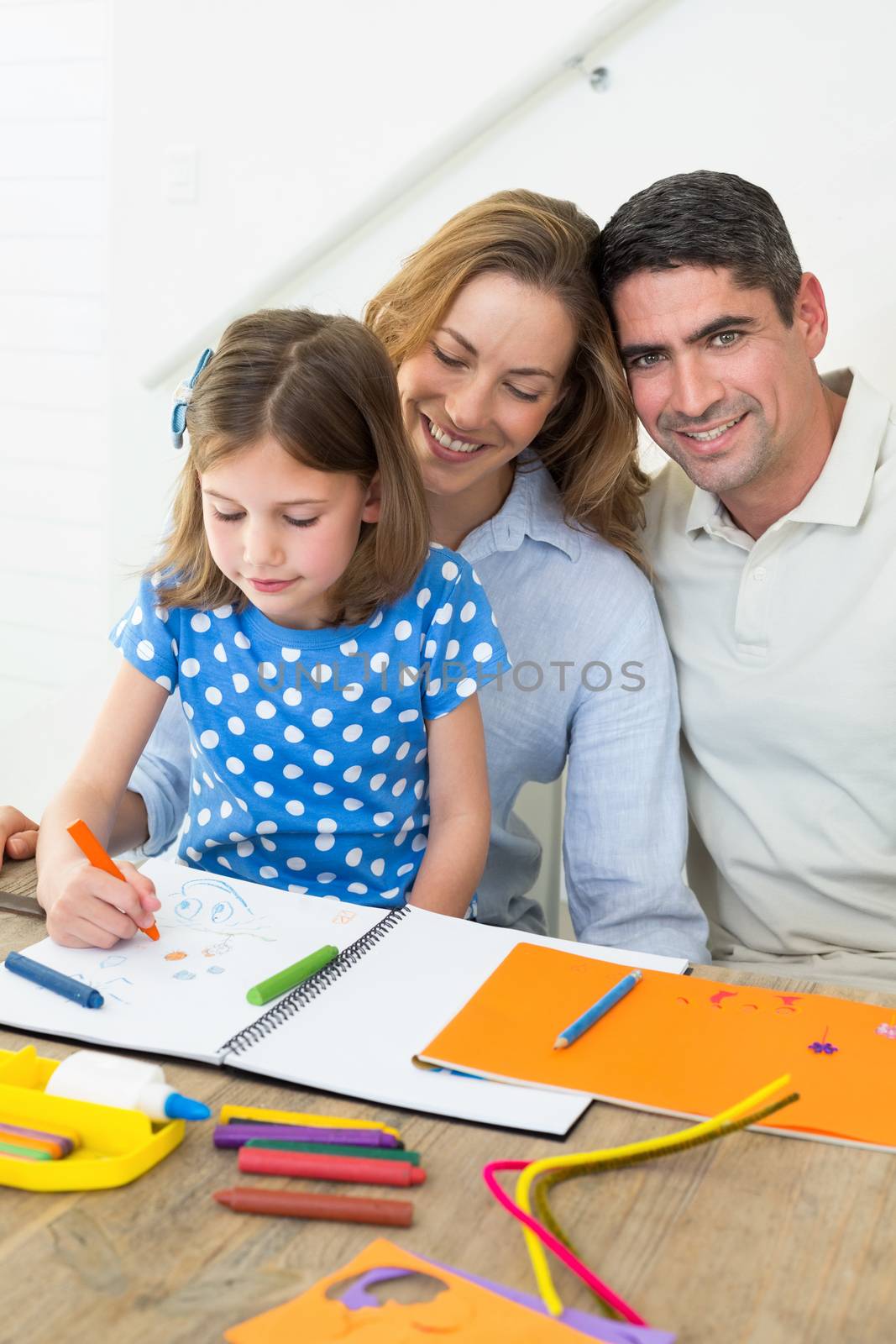 Portrait of happy man with daughter and woman coloring at home