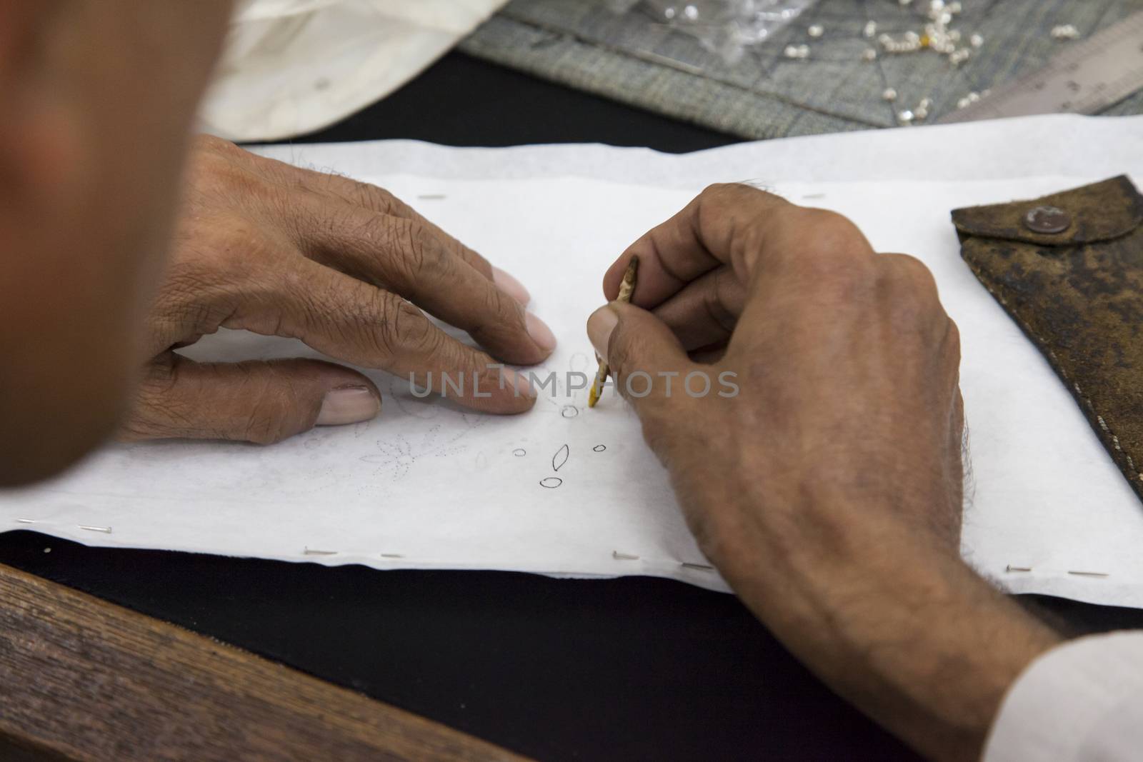 Worker drawing stencil motif on cloth by haiderazim