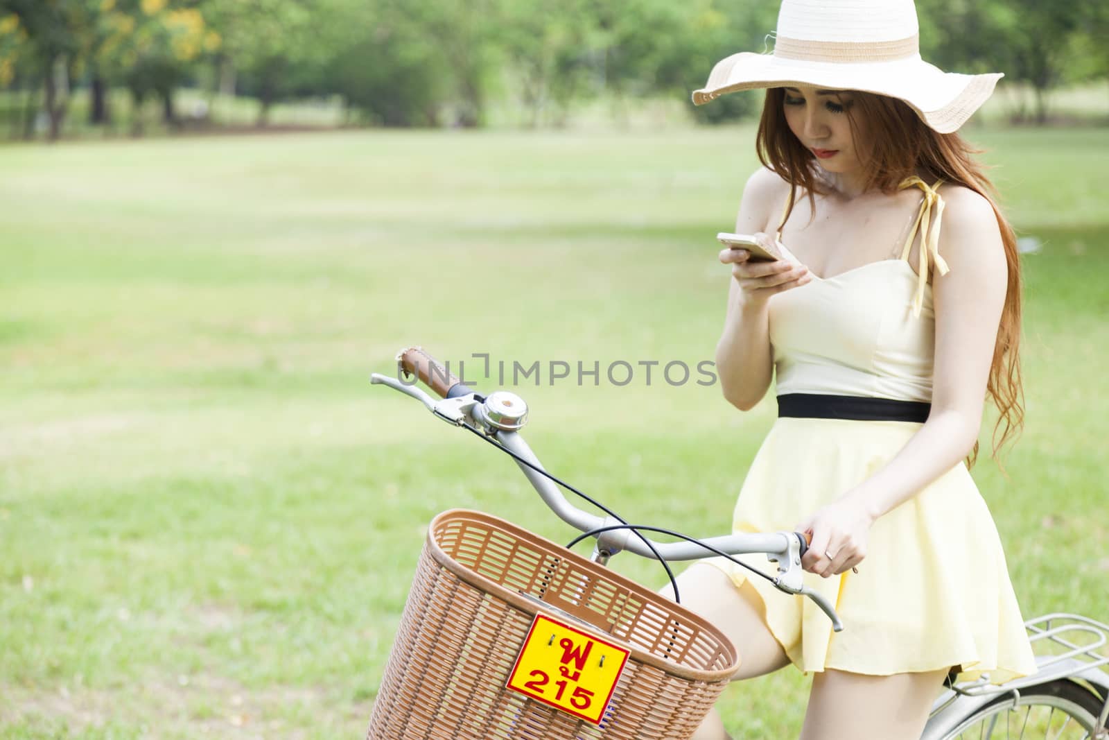 Woman playing phone While cycling in the park.