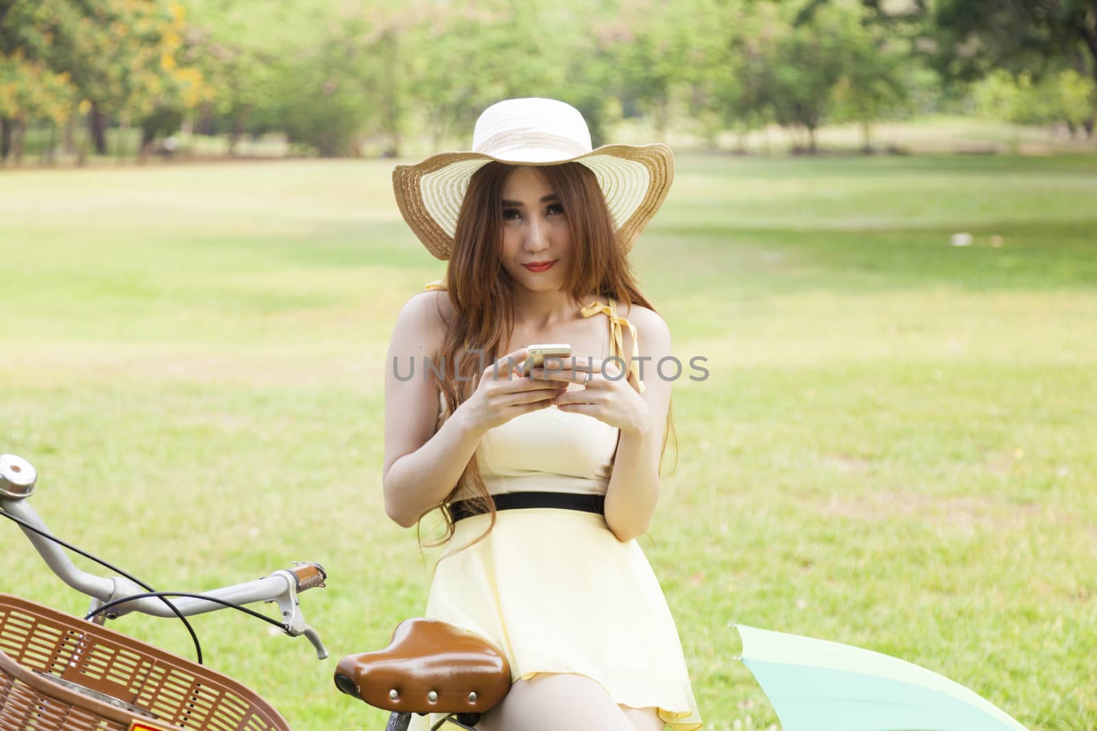 Woman play smart phone.on bike in lawn.in park.