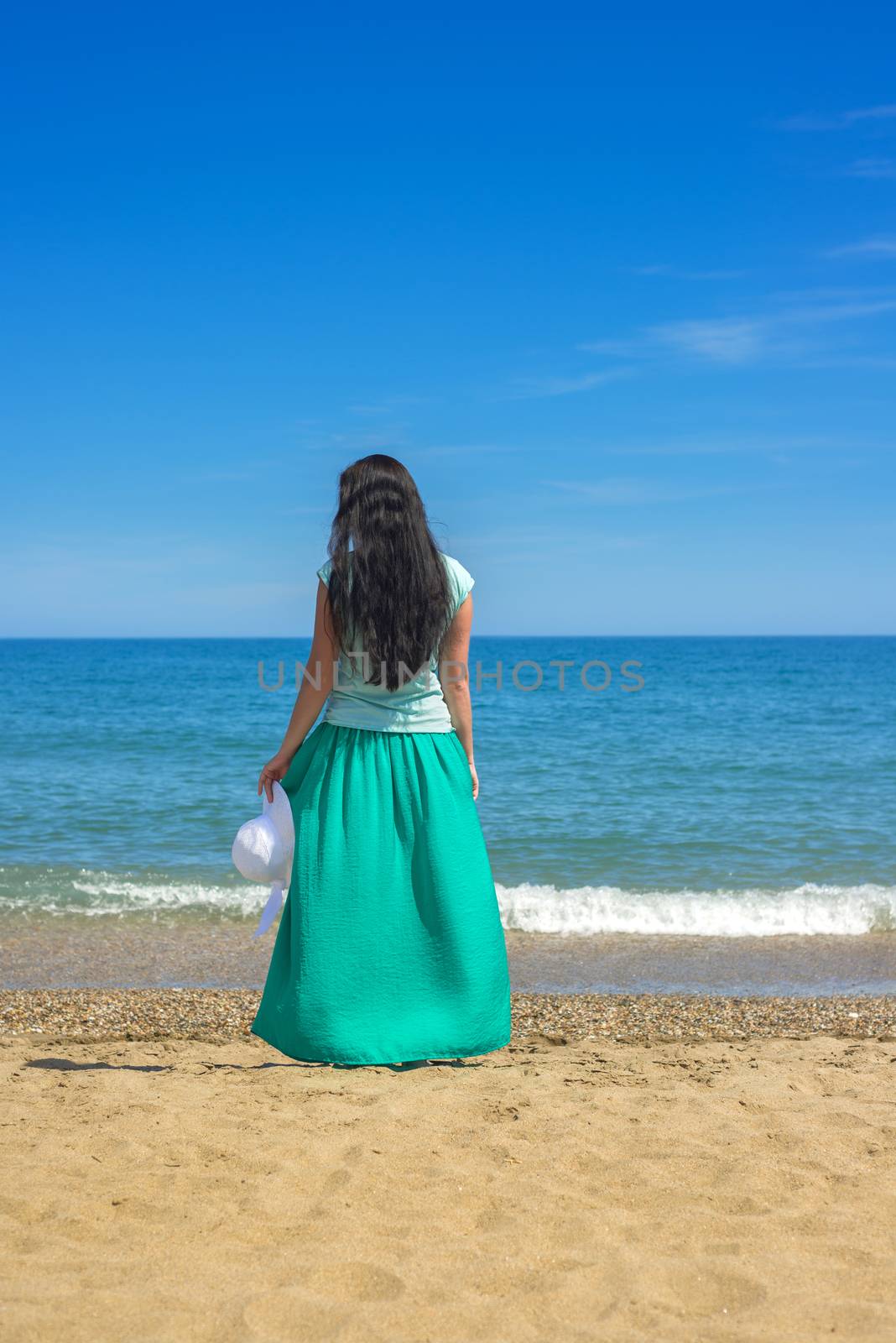 Brunette with long hair standing alone on the sandy beach
