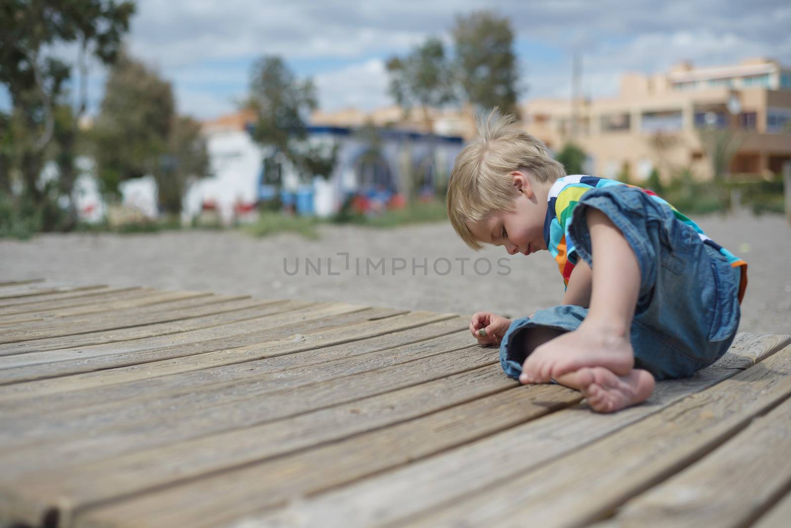 Boy playing on a wooden walkway on the beach by anytka