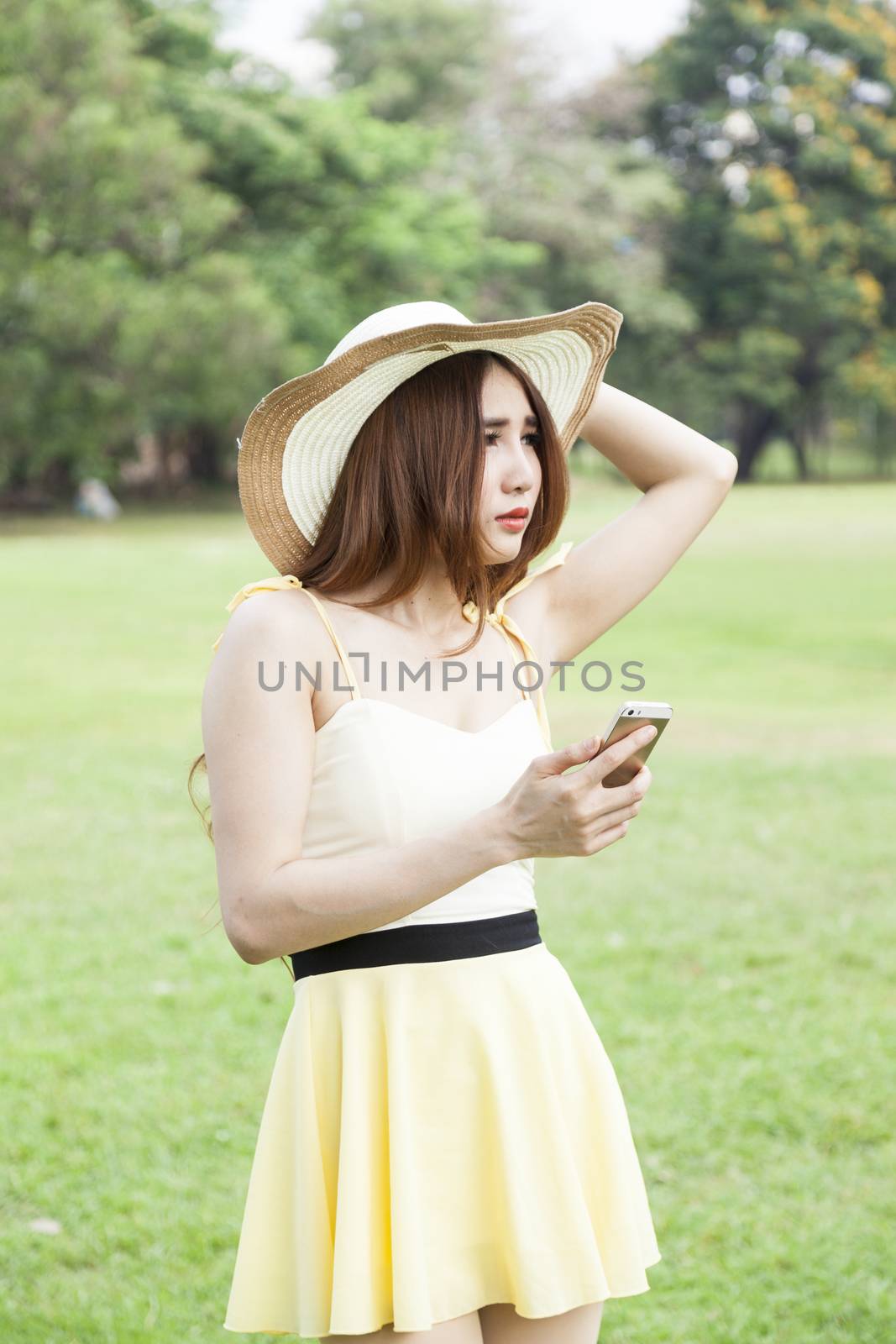 Woman play smart phones. Woman with hat standing in a park with a phone.