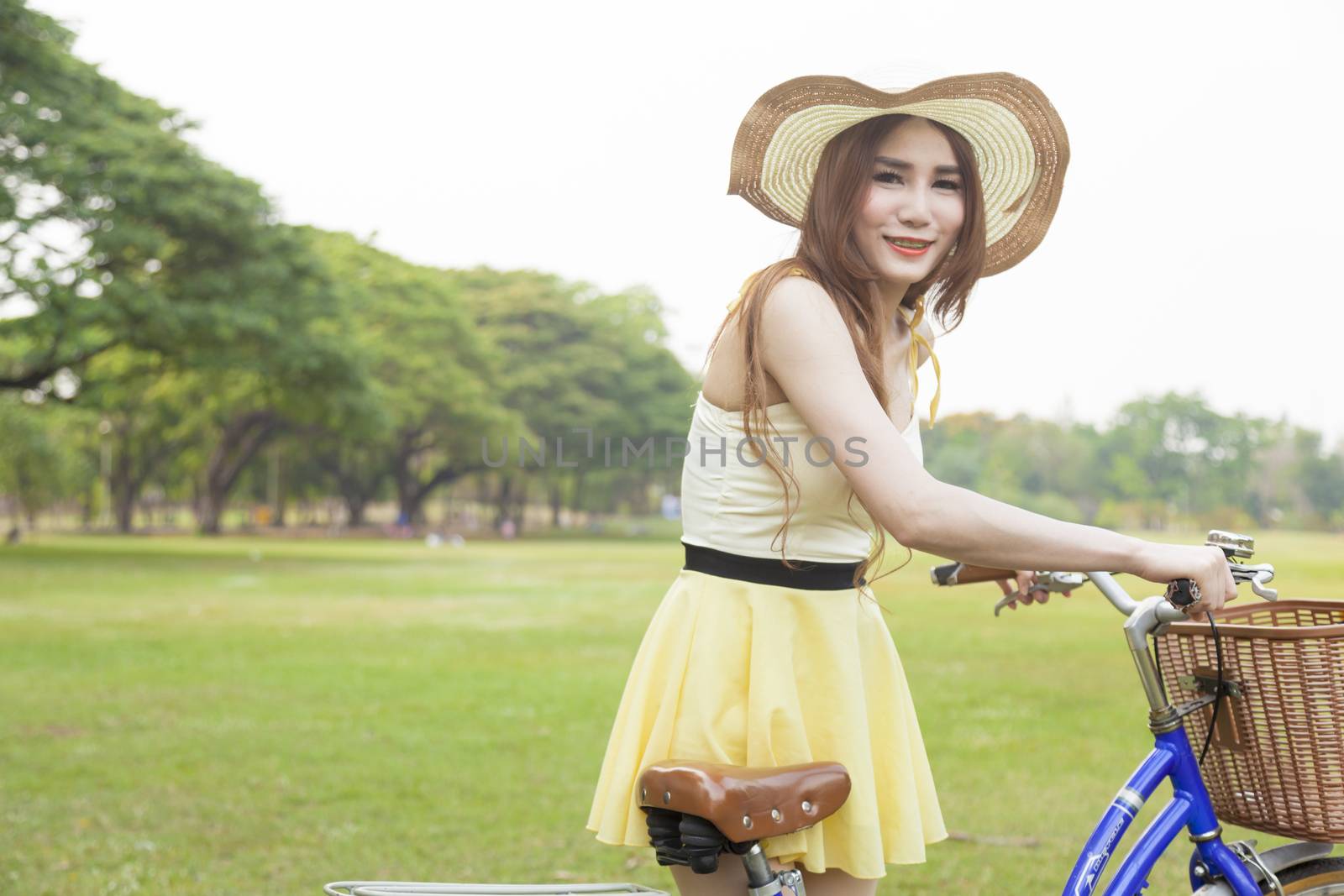 Woman with bike on the lawn. In the park on the lawn. With shady trees and natural