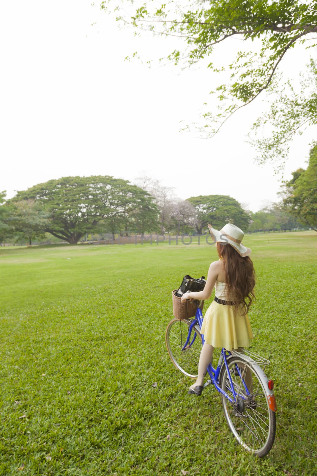 Woman riding a bicycle. Woman with hat riding a bicycle in the park.