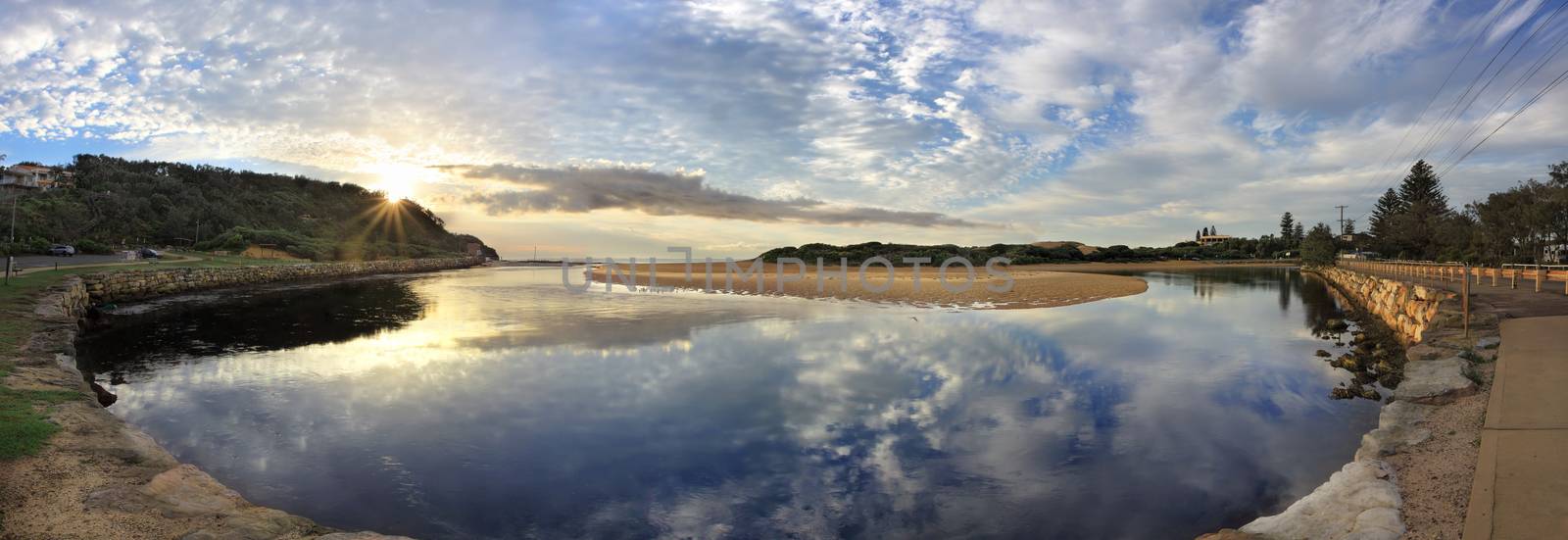 Narrabeen Lakes Entrance panorama early morning with sunburst over the North Narrabeen headland.  Narrabeen surf club at right.  The lake snakes around until it meets the ocean at North Narrabeen.  