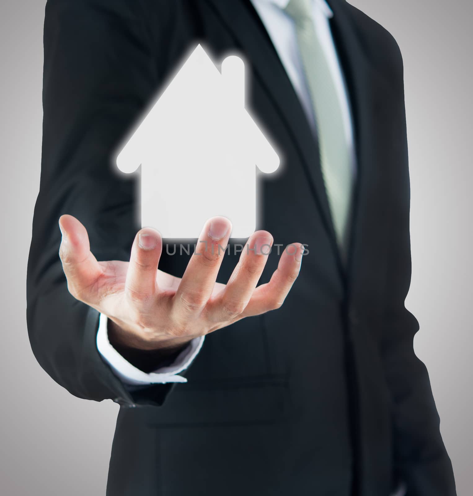 Businessman standing posture hand holding house icon isolated on over gray background