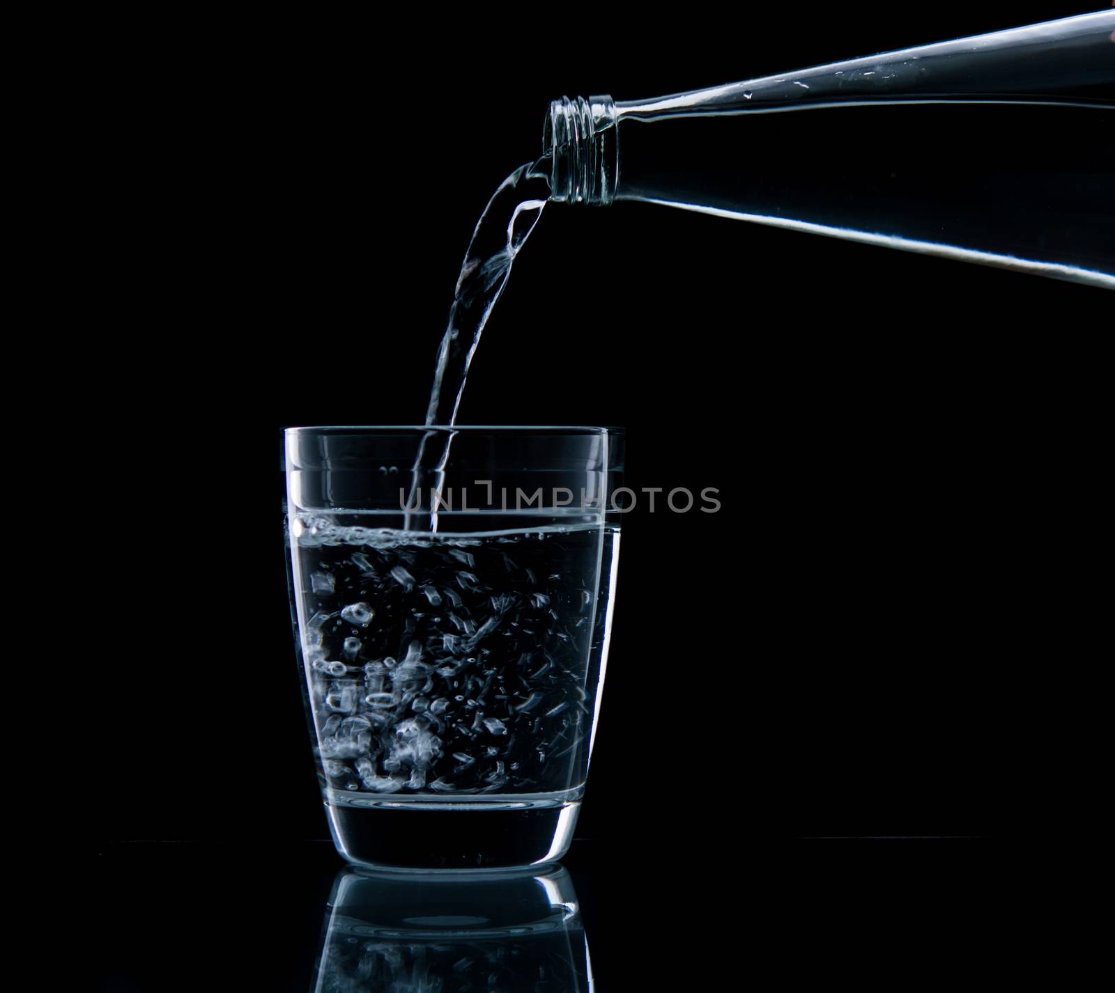 Pouring water on glass on over black background