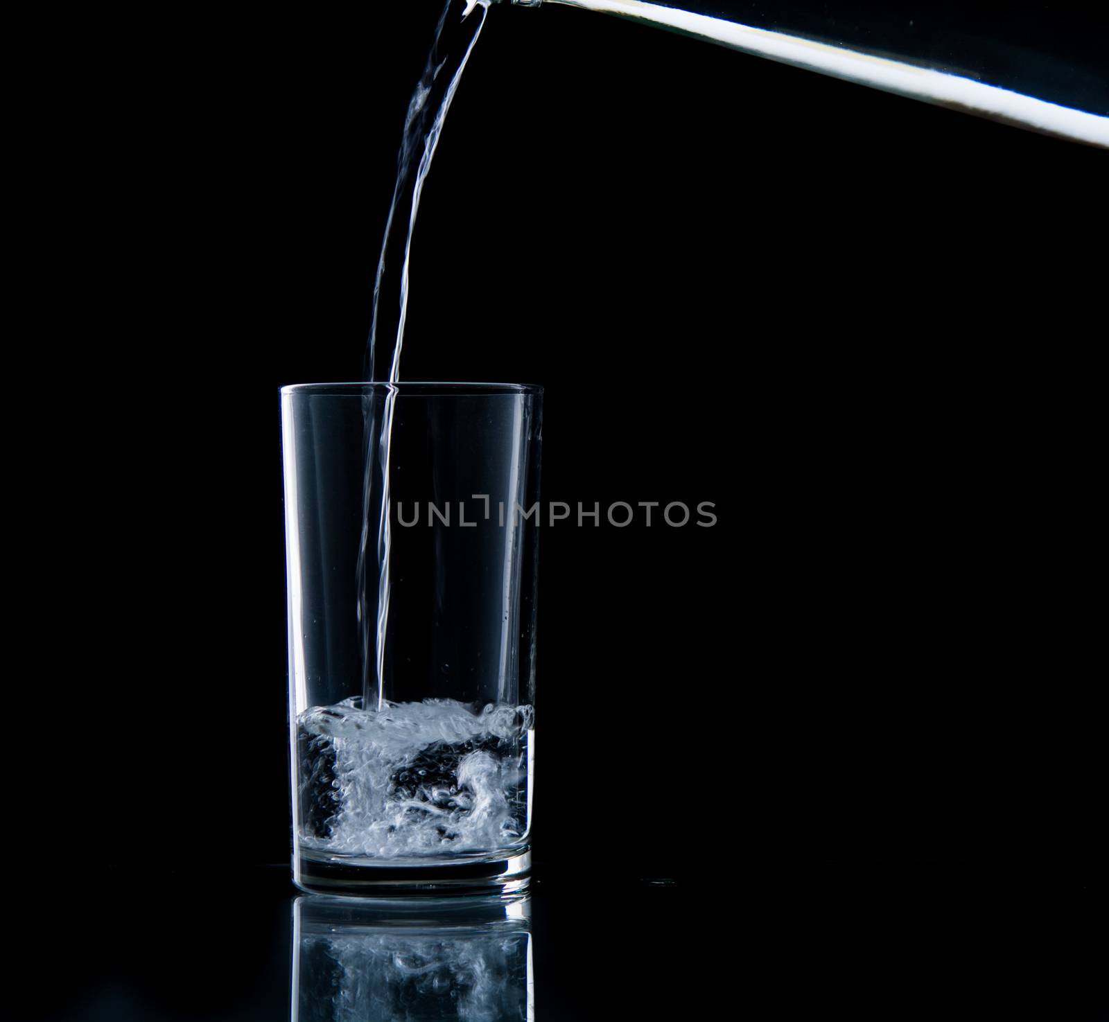 Pouring water on glass on over black background