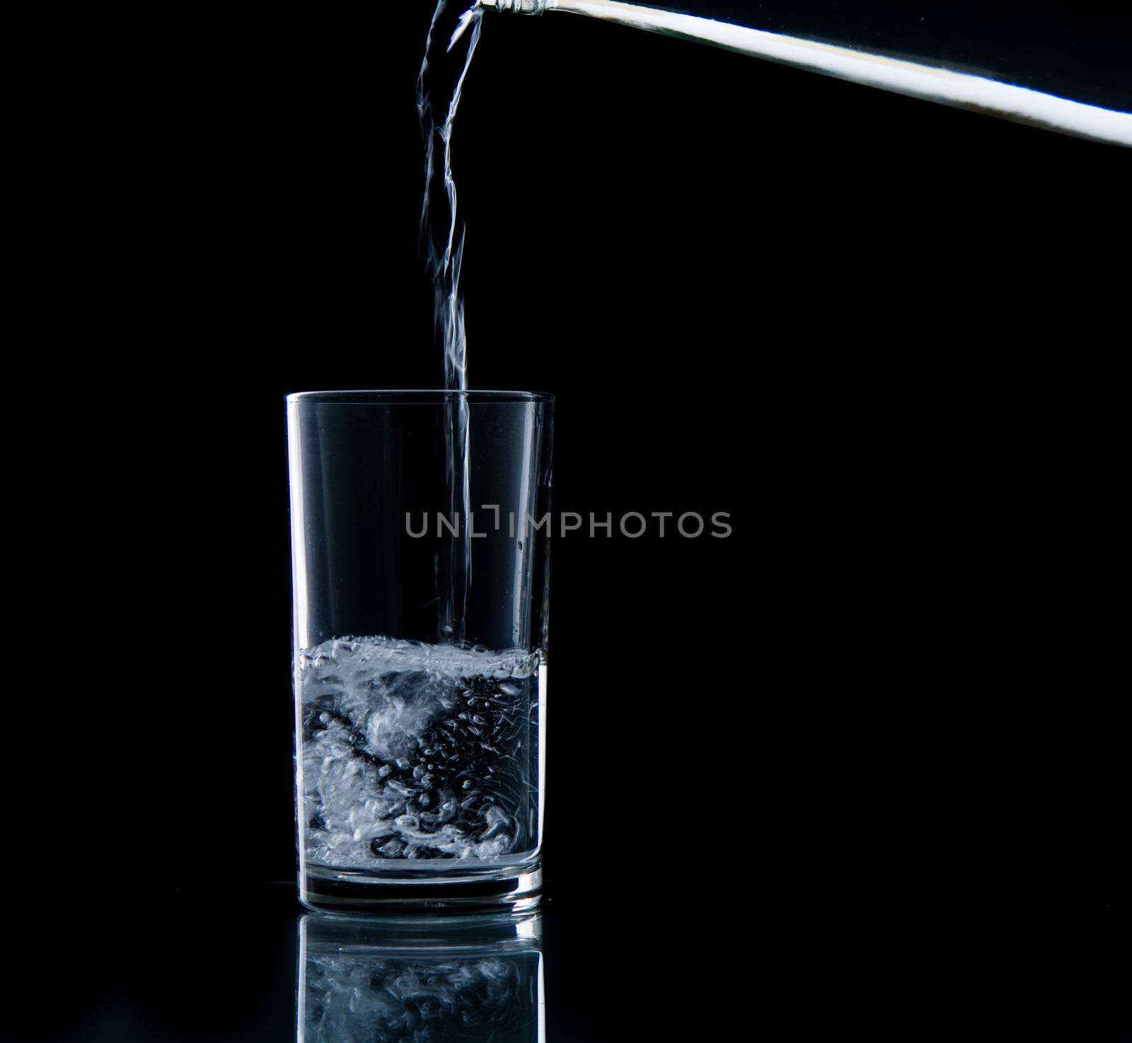 Pouring water on glass on over black background