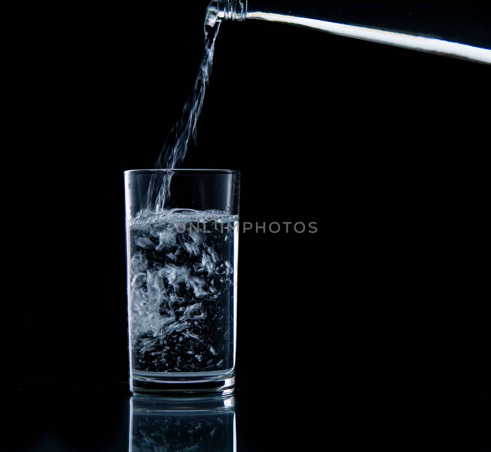 Pouring water on glass on over black background