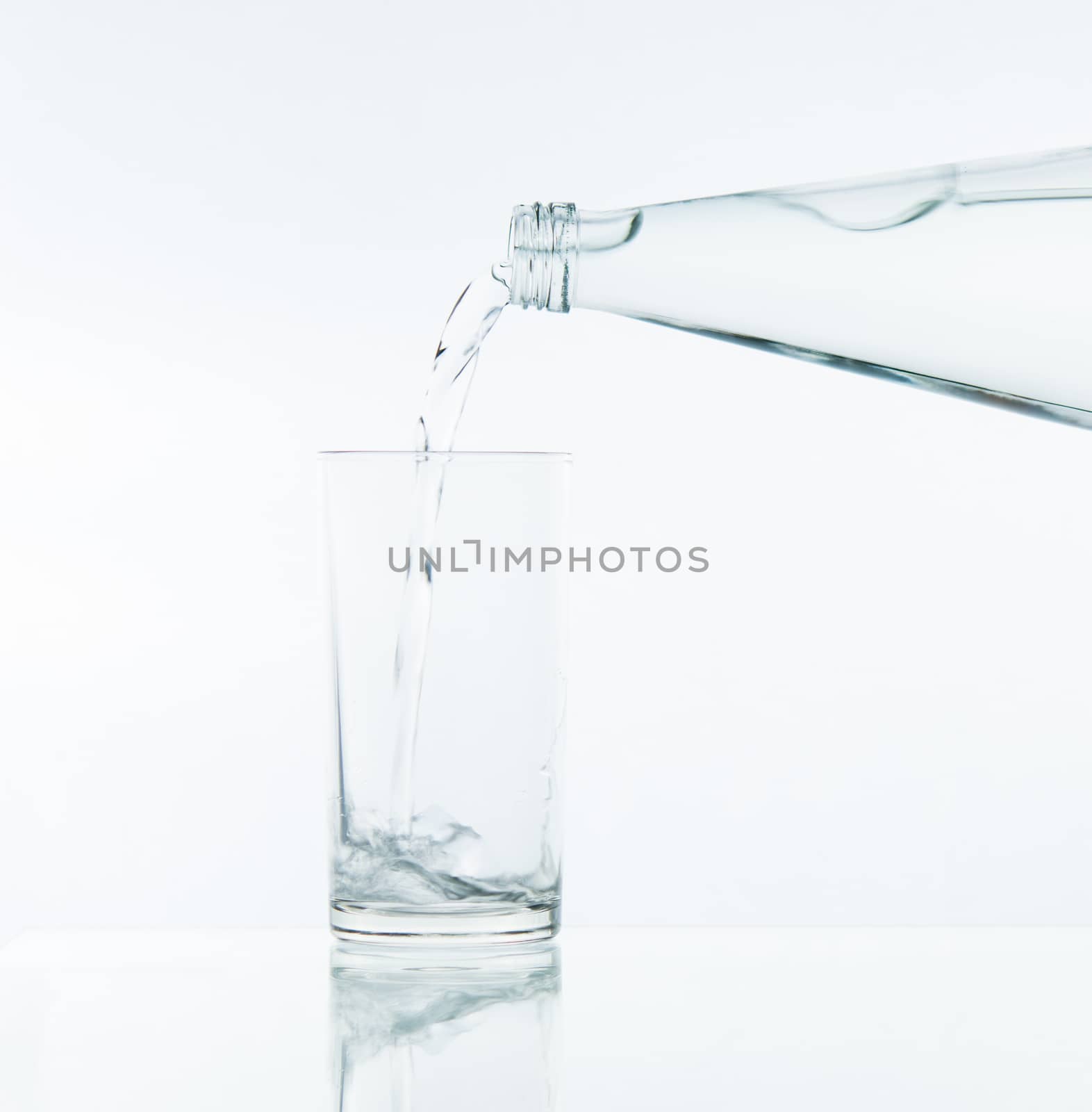 Pouring water on glass on over white background