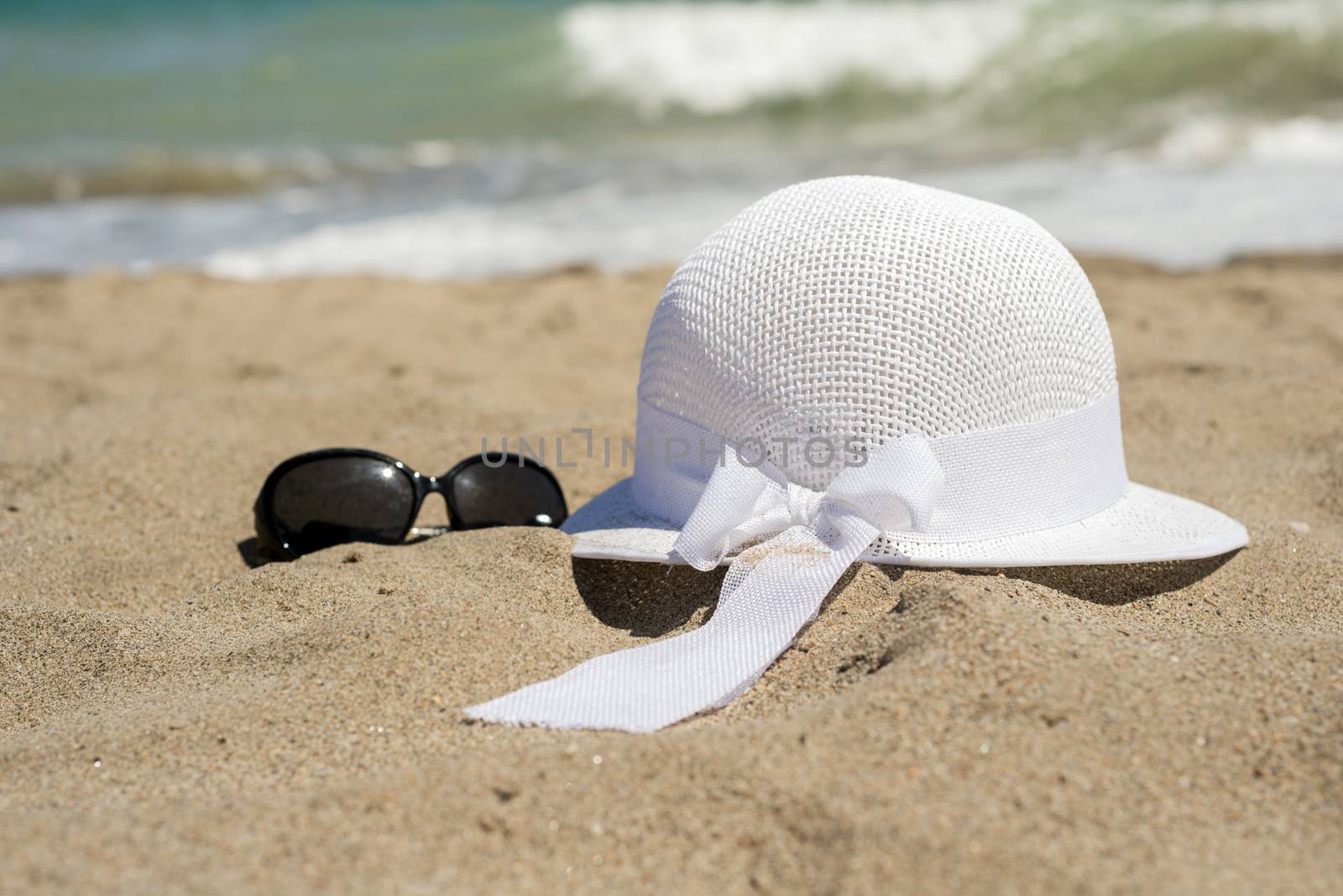 White wicker hat and black sunglasses on the beach