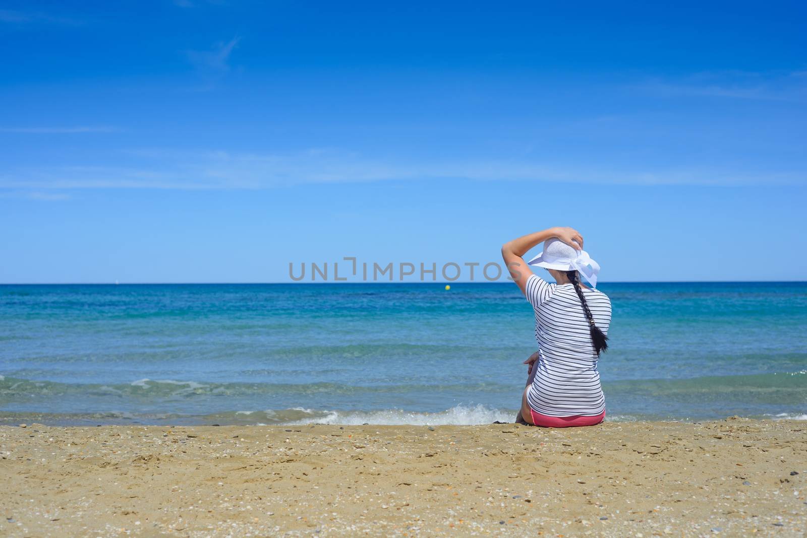 Young brunette  woman sitting on sandy beach and looking to a sea