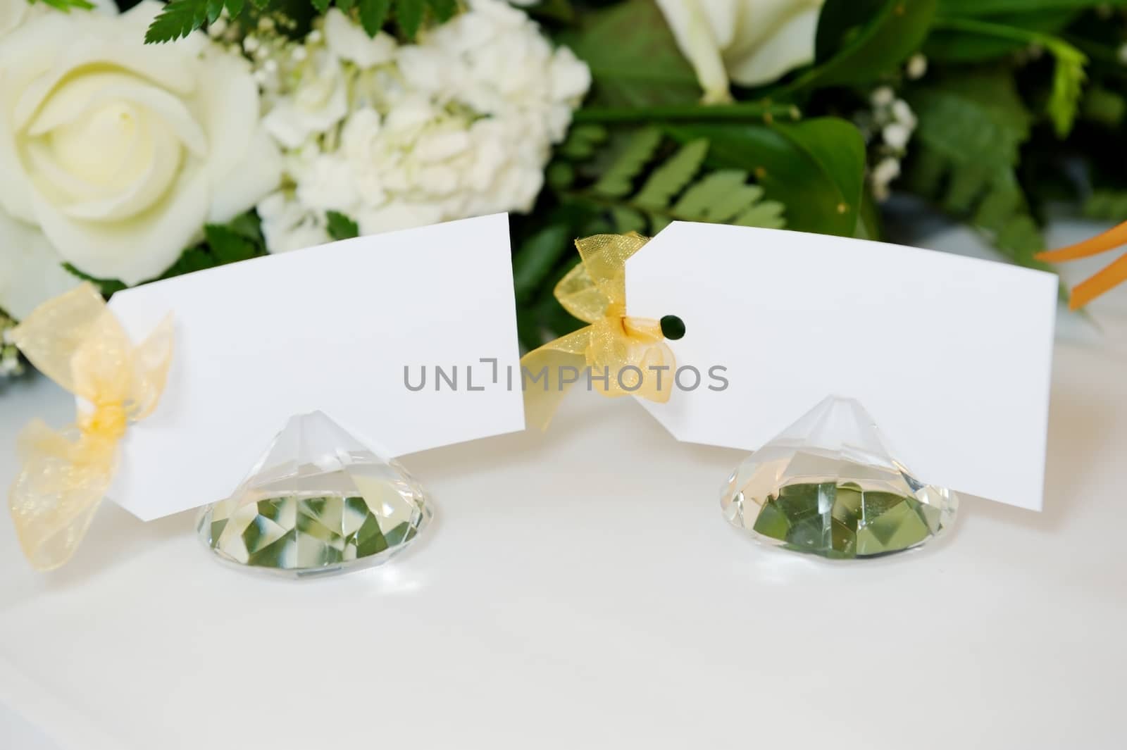 Closeup detail of wedding reception place cards on top table with white floral arrangement