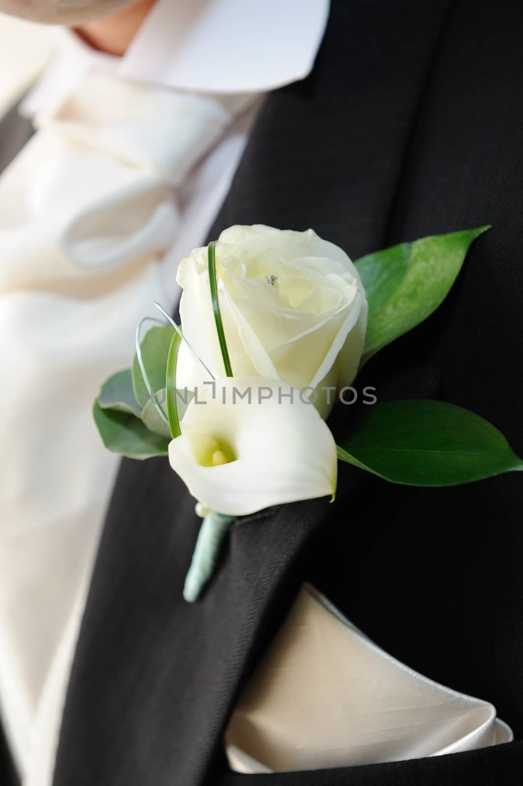 Grooms white roses and white lily in buttonhole.