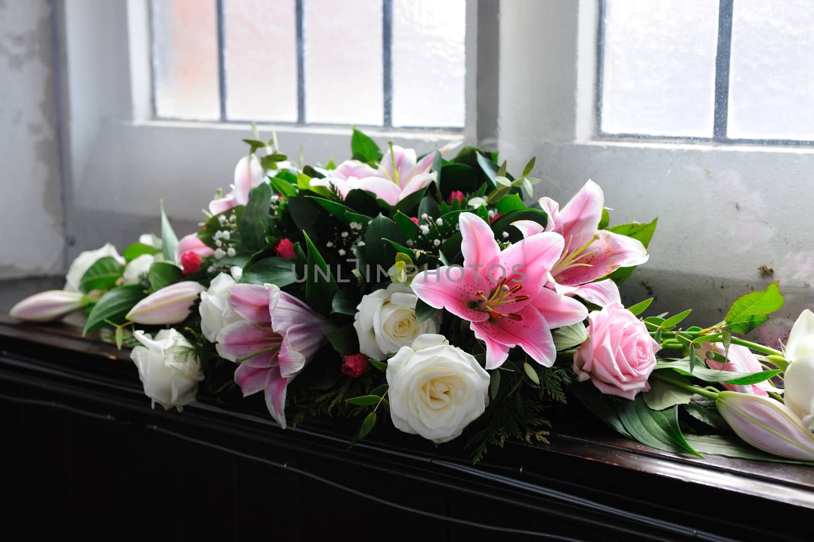 Pink and white flowers decorate church for wedding. Lilies and roses.