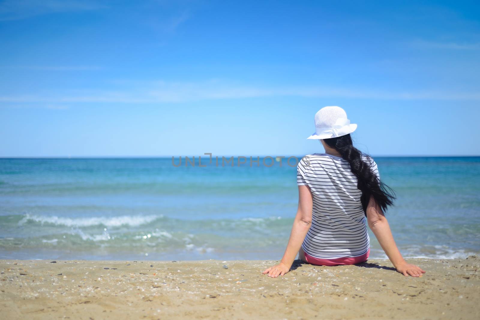 Young woman sitting on sand and looking to a sea by anytka