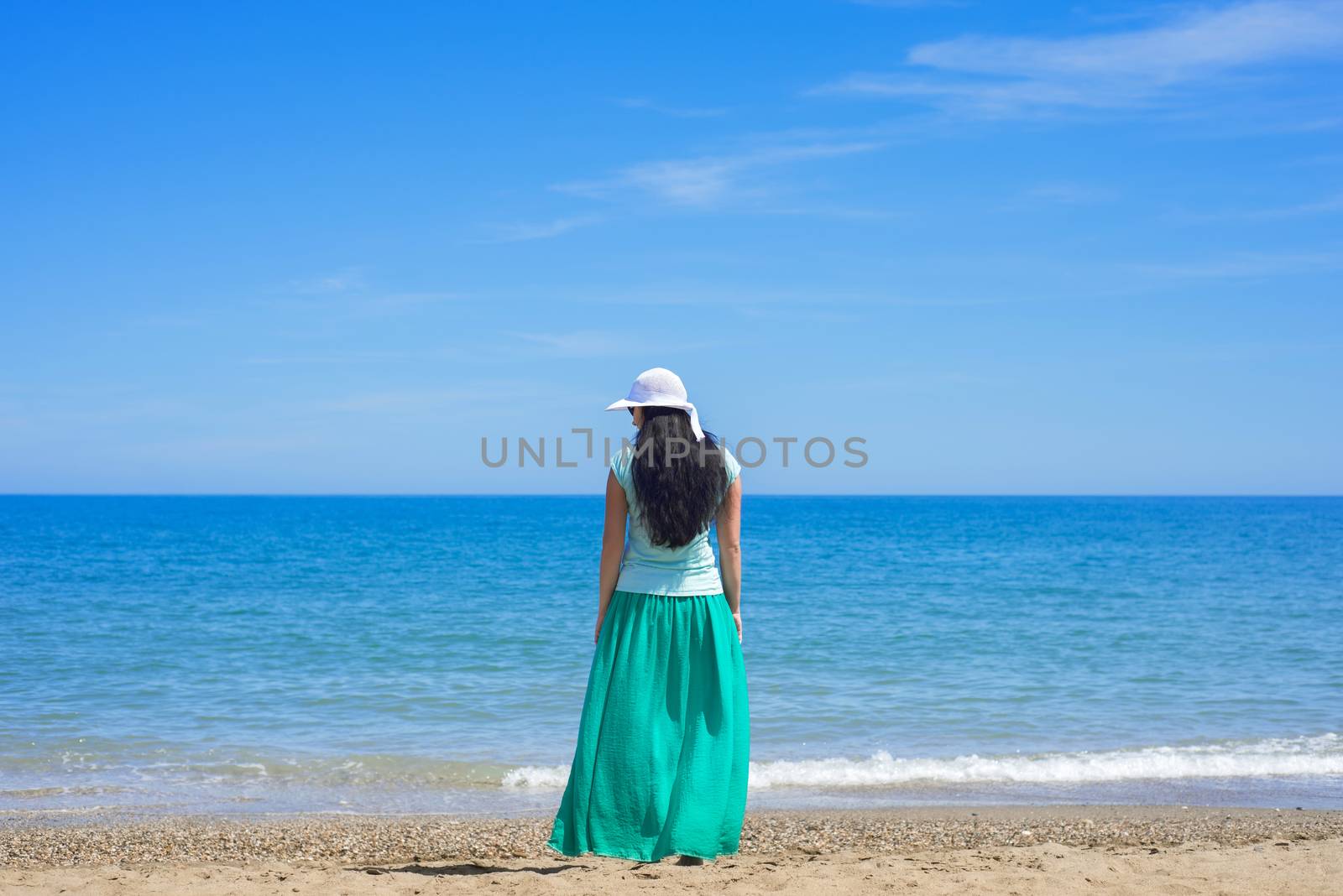 Brunette female with long hair standing alone on the sandy beach