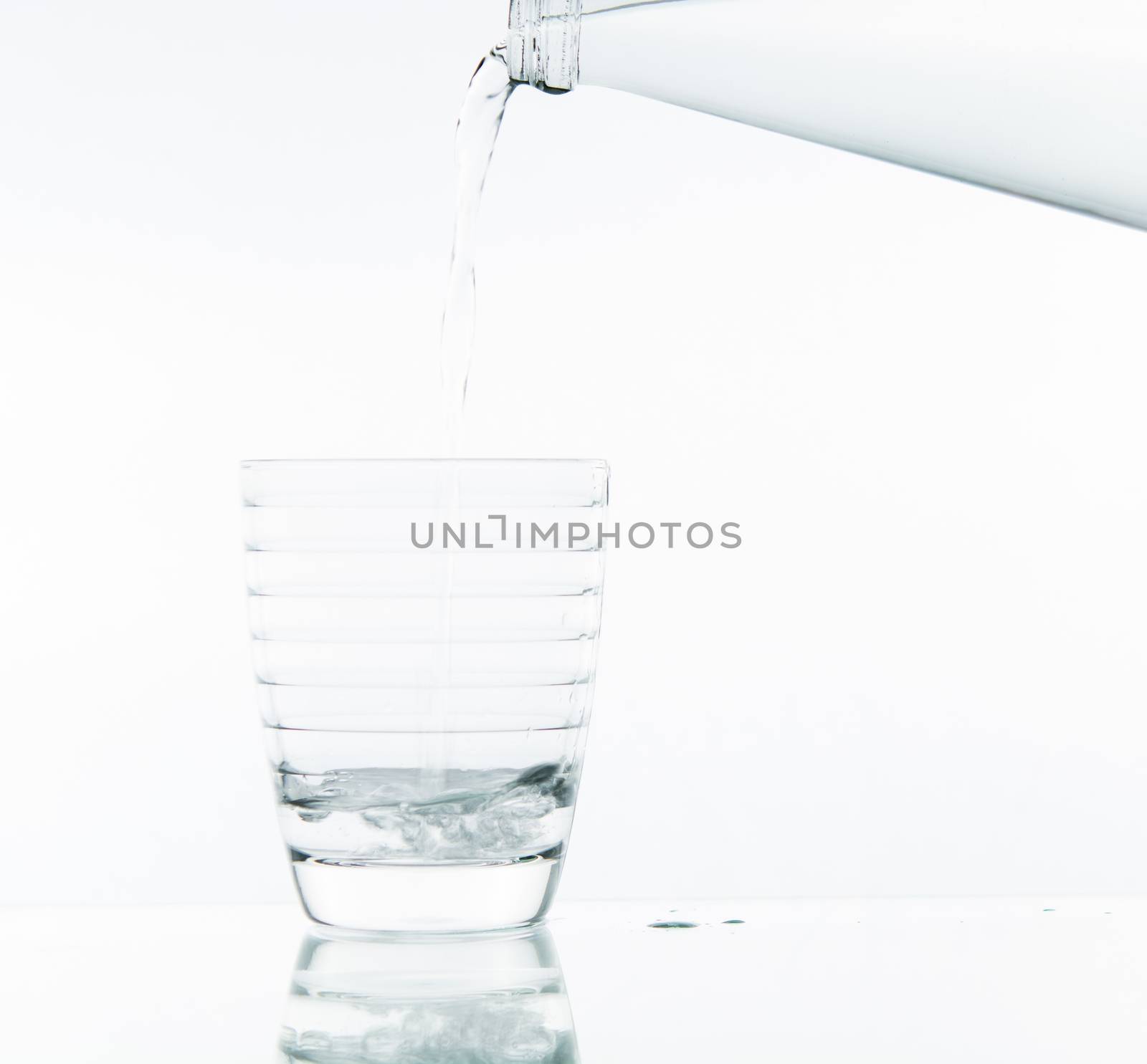 Pouring water on glass on over white background