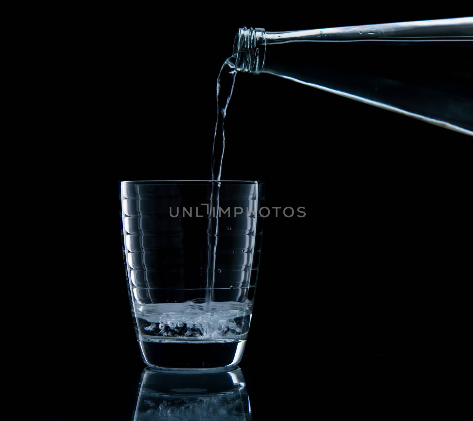 Pouring water on glass on over black background