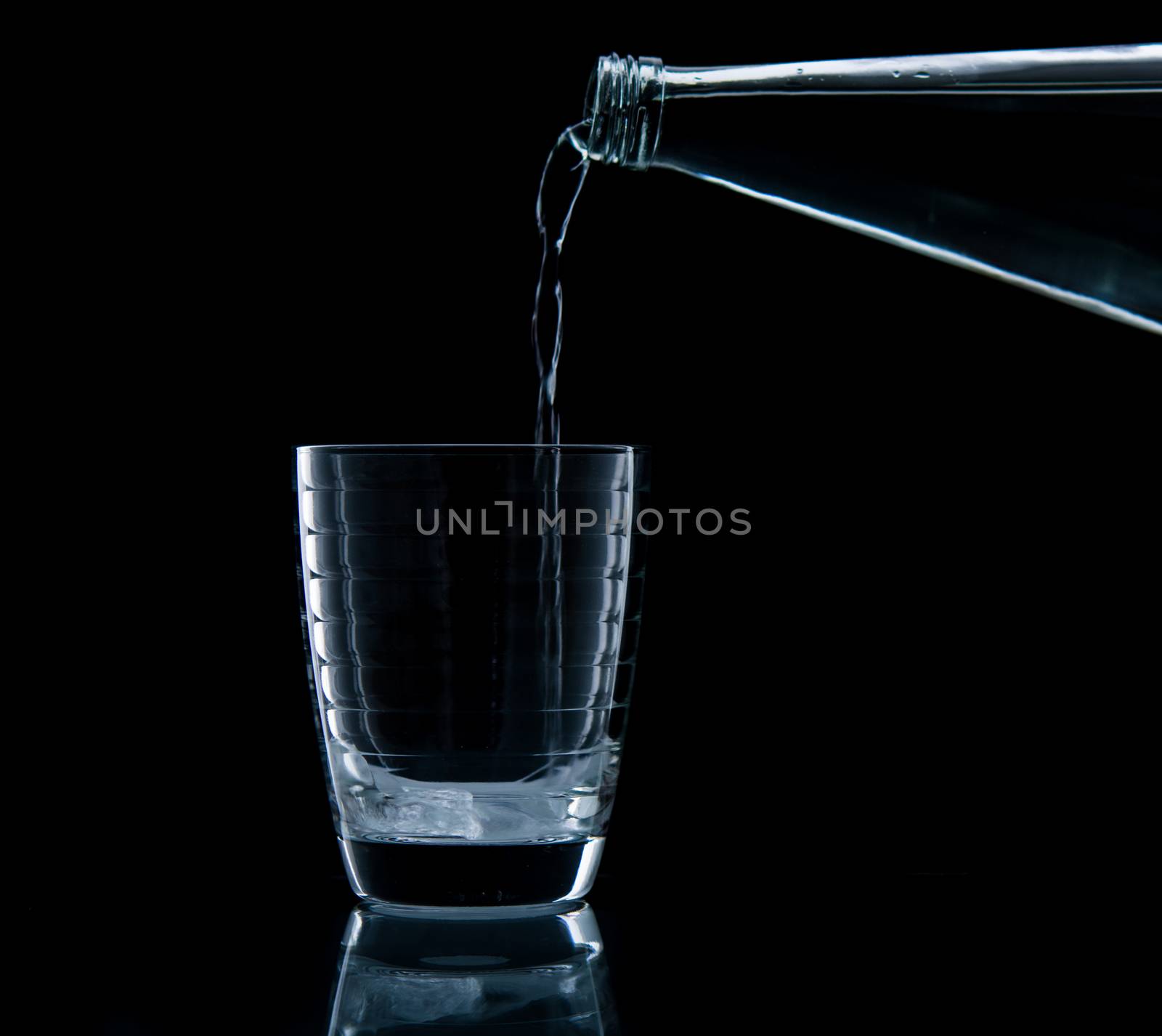 Pouring water on glass on over black background