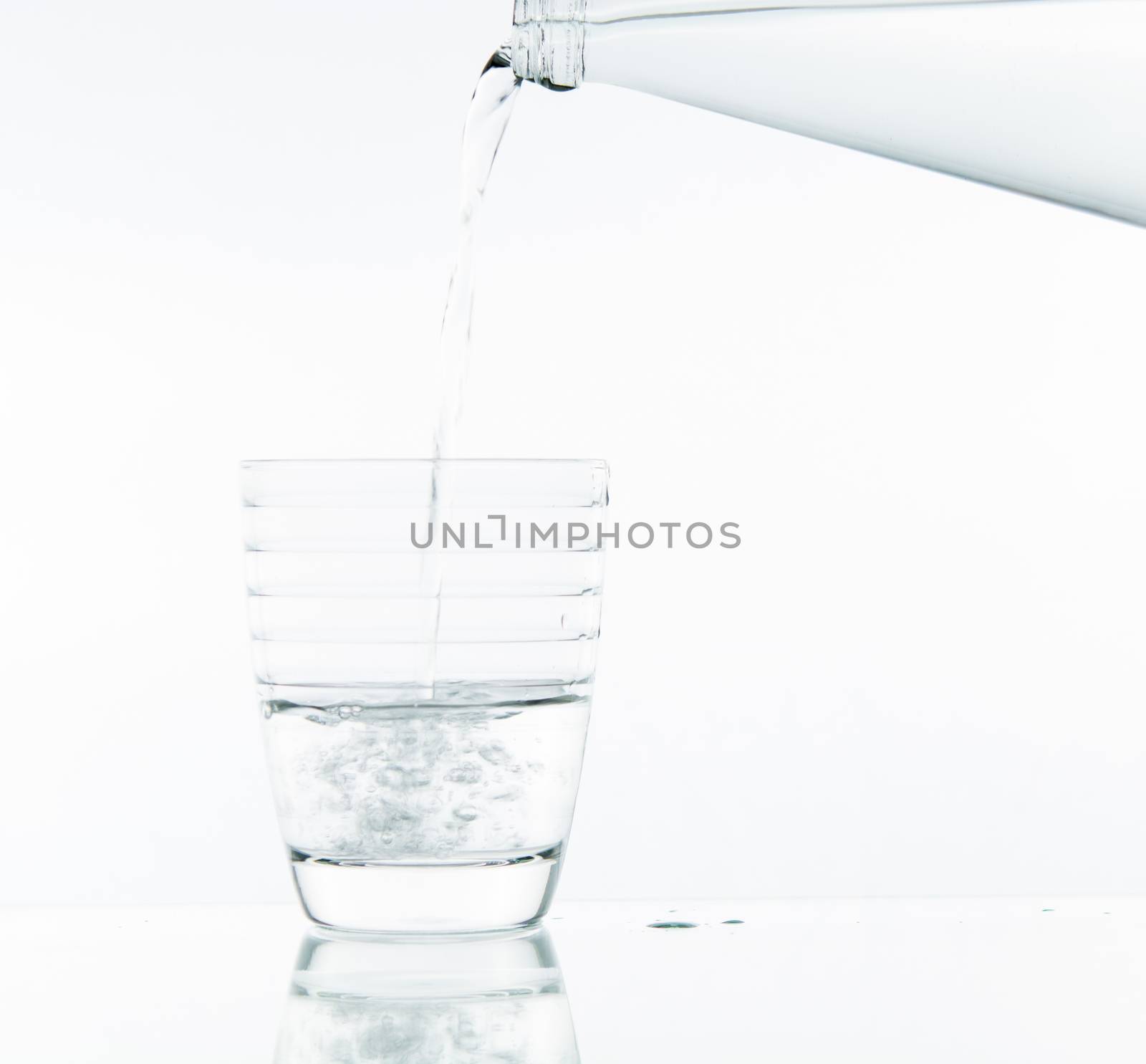 Pouring water on glass on over white background